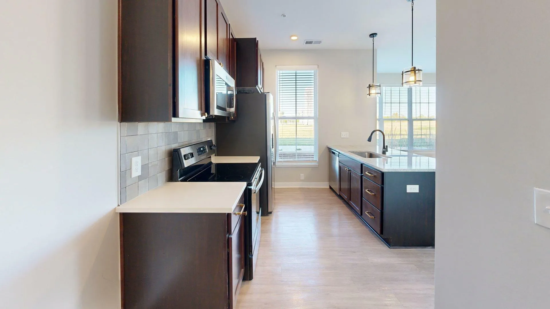 Modern kitchen with dark wood cabinets, sleek countertops, and elegant lighting, perfect for culinary enthusiasts.