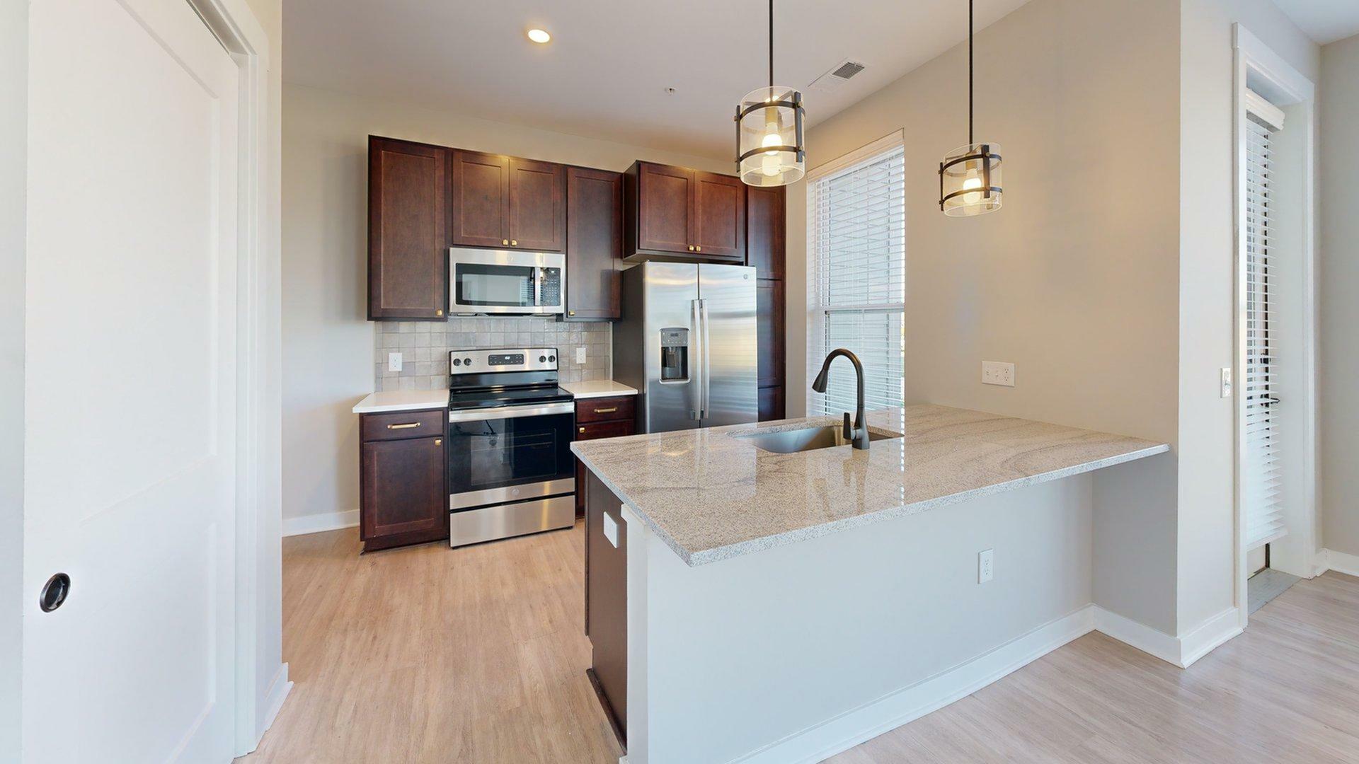 Modern kitchen with elegant dark wood cabinetry, stainless steel appliances, and a stylish granite countertop breakfast bar.
