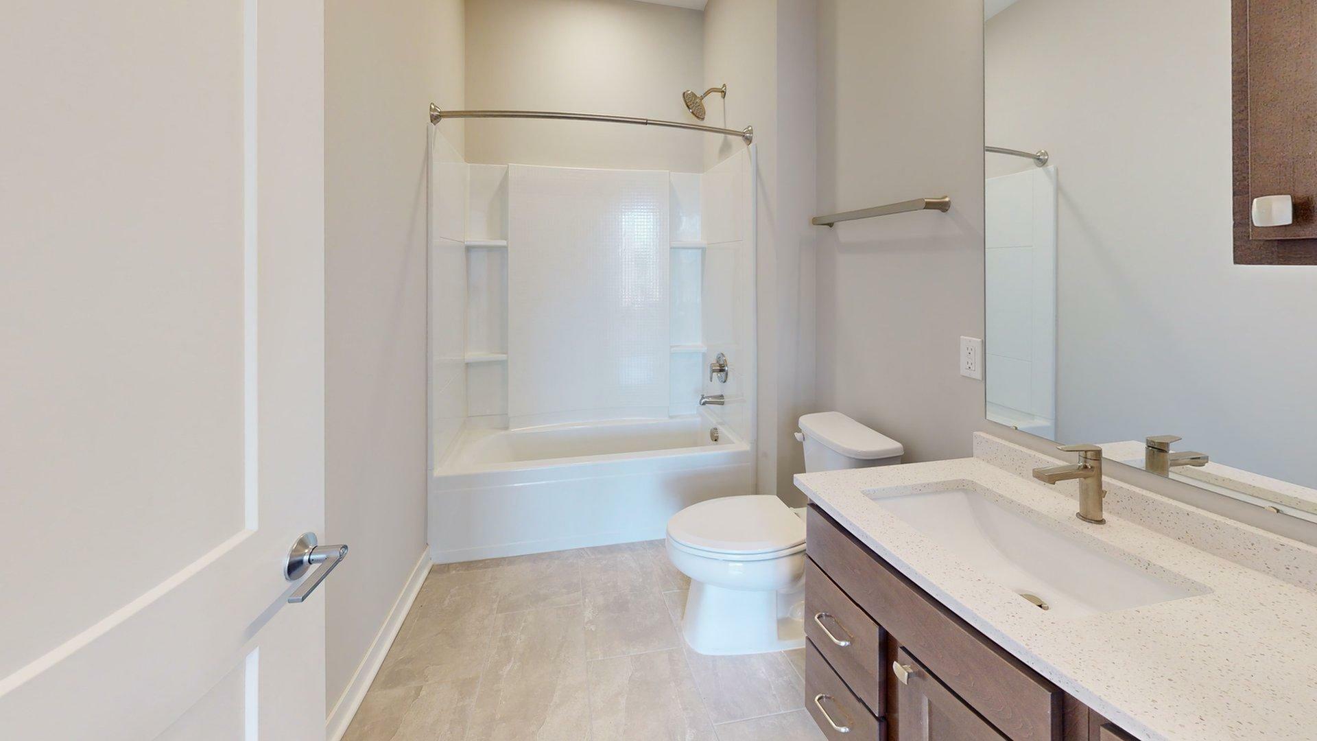 Modern bathroom featuring a sleek white bathtub, elegant sink with storage, and neutral tile flooring.
