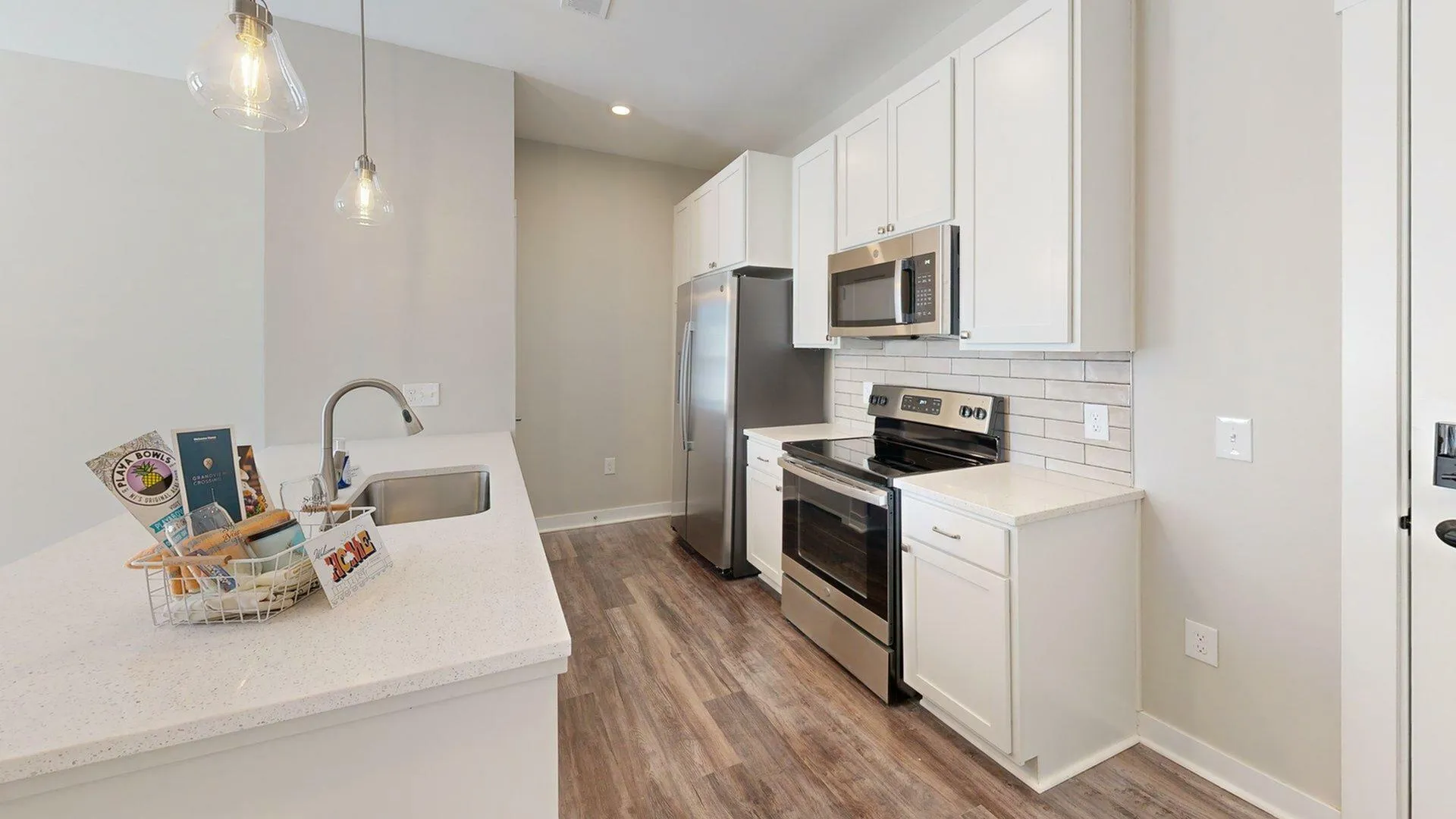 Contemporary kitchen with sleek stainless steel appliances, elegant white cabinetry, and inviting pendant lighting over a spacious quartz countertop.