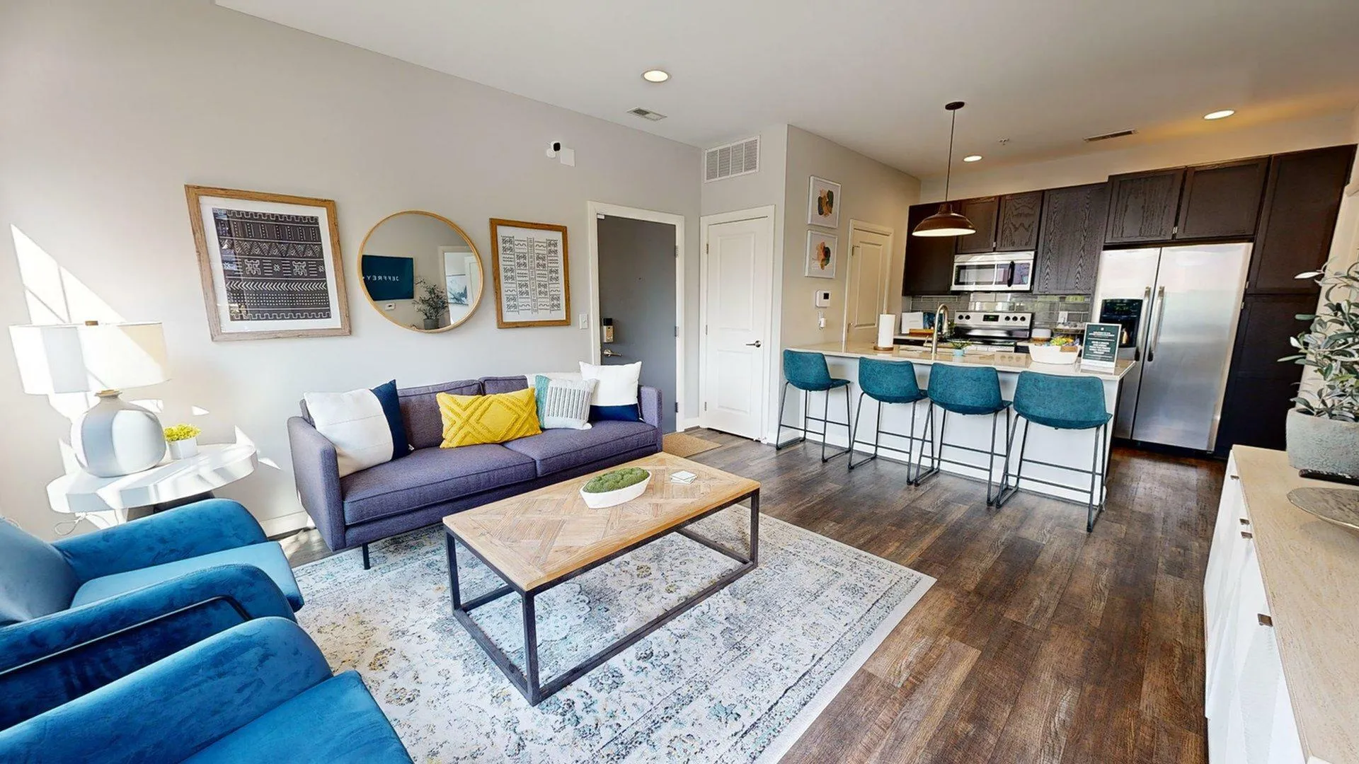 Bright, modern open-concept living space featuring a cozy seating area, stylish kitchen with bar stools, and elegant decor.