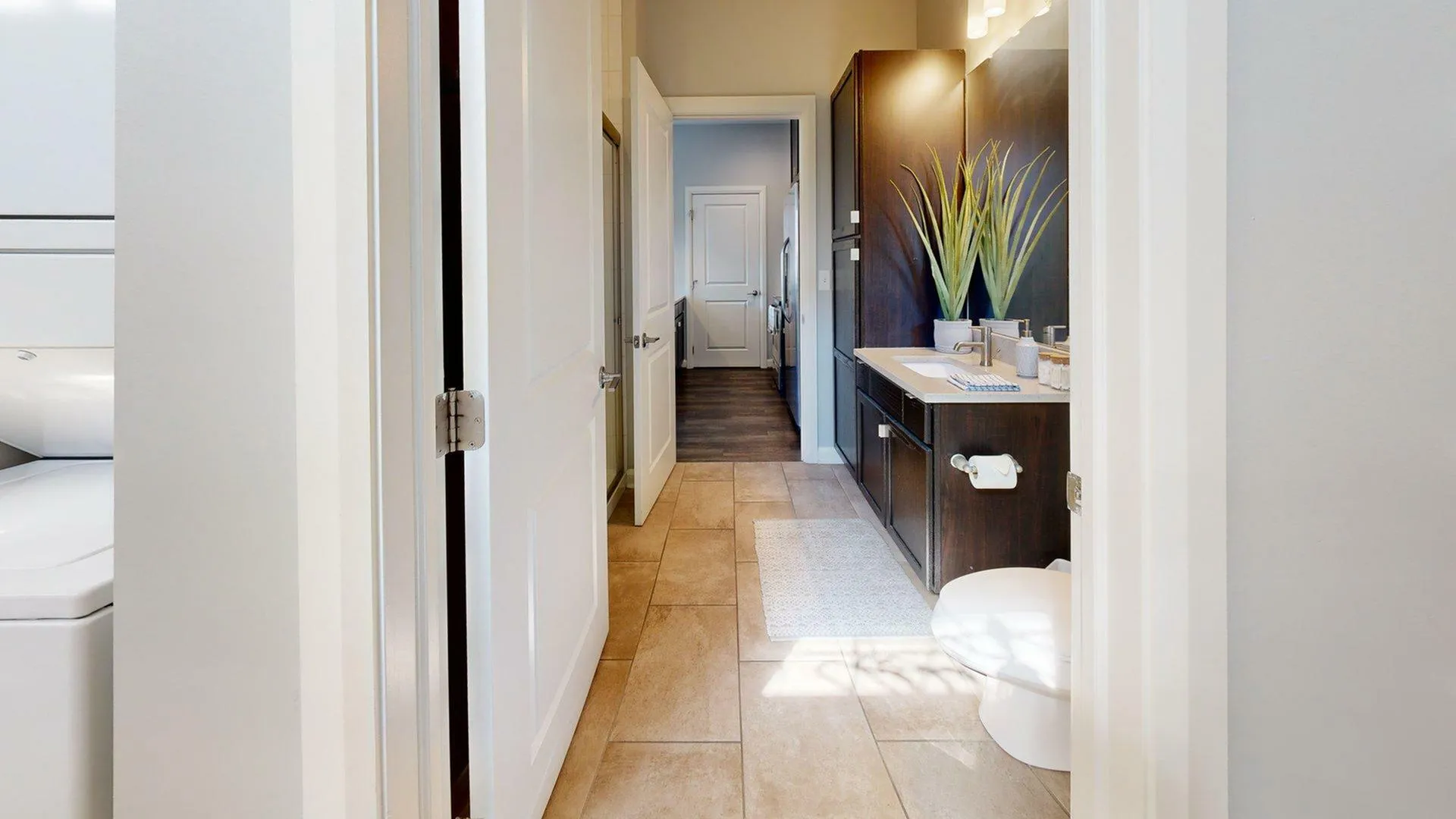 Contemporary hallway view showcasing a sleek bathroom with stylish cabinetry and modern decor, leading into a bright living space.