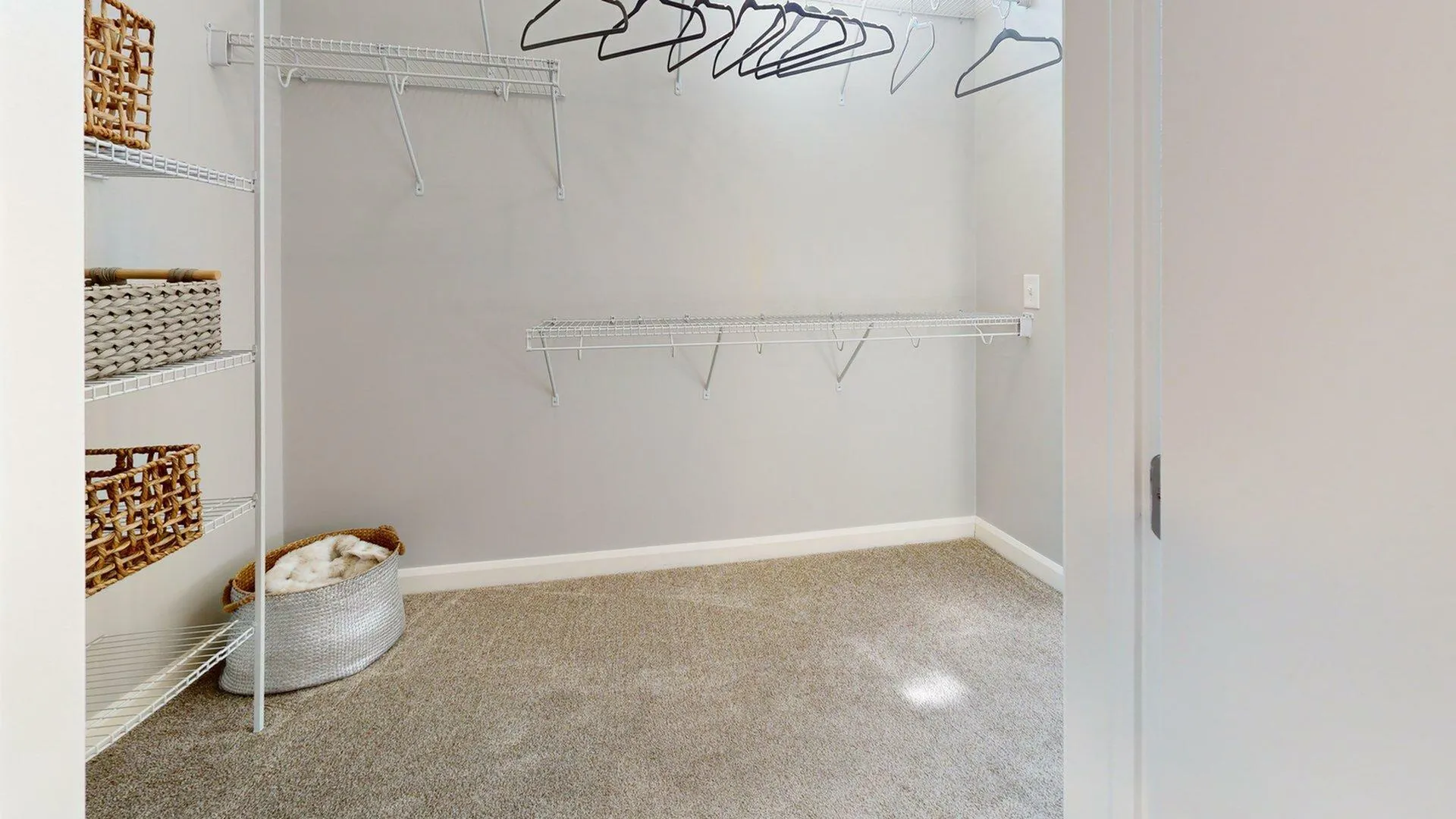 Spacious walk-in closet with ample shelving and hanging space, featuring elegant woven baskets for stylish storage solutions.