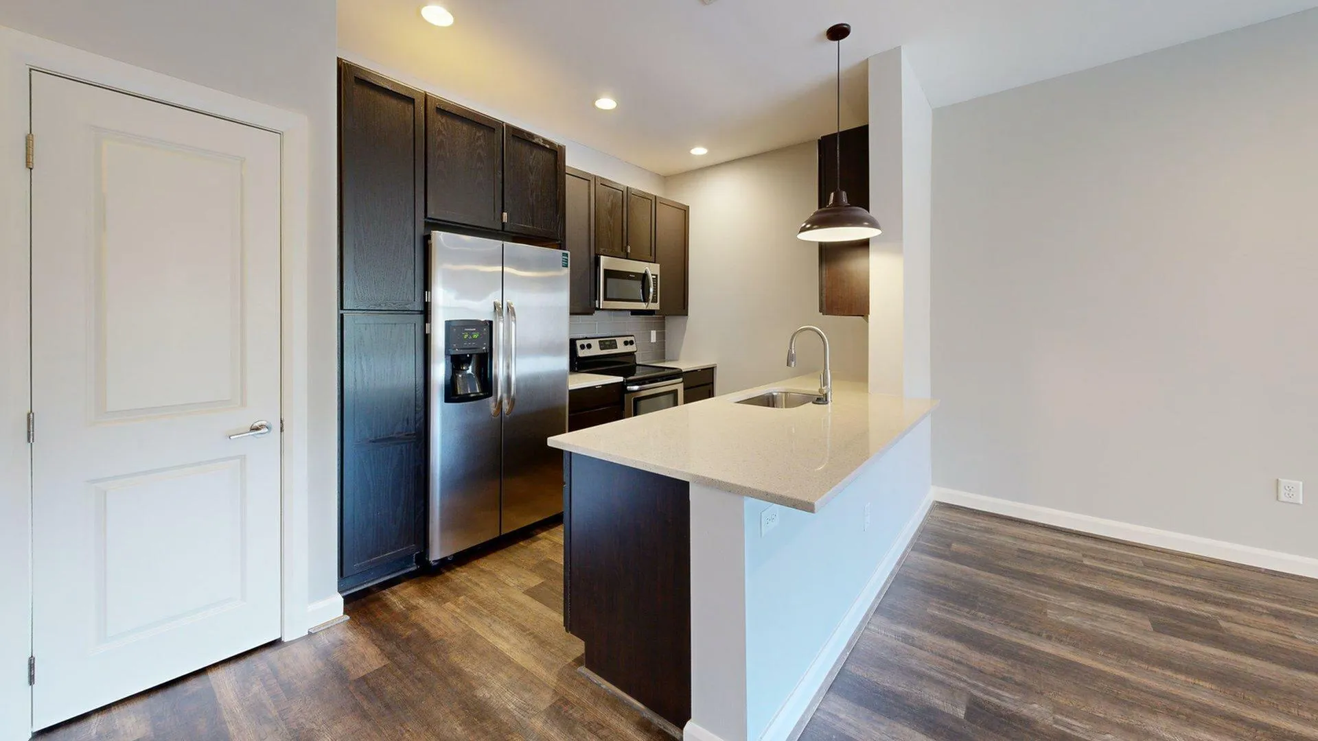 Modern kitchen with sleek dark cabinets, stainless steel appliances, and quartz countertops.