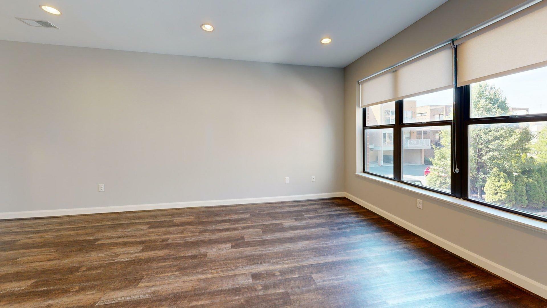 Bright, modern room with large windows and sleek wooden flooring, perfect for a cozy living space.