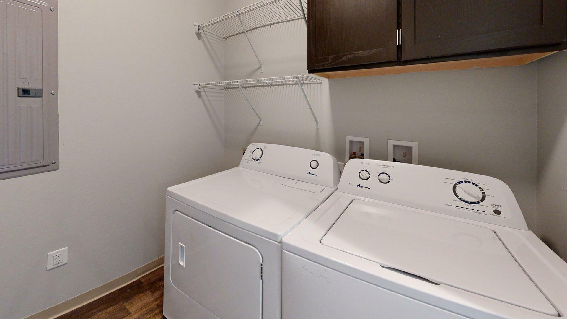 Modern laundry room equipped with washer and dryer, featuring ample shelving and sleek cabinetry.