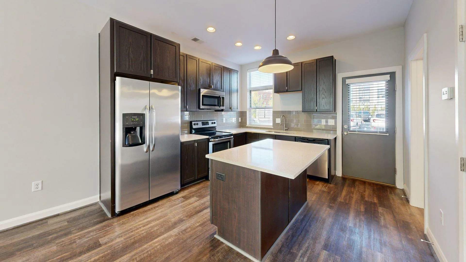 Modern kitchen with sleek dark cabinetry, stainless steel appliances, and a stylish central island.