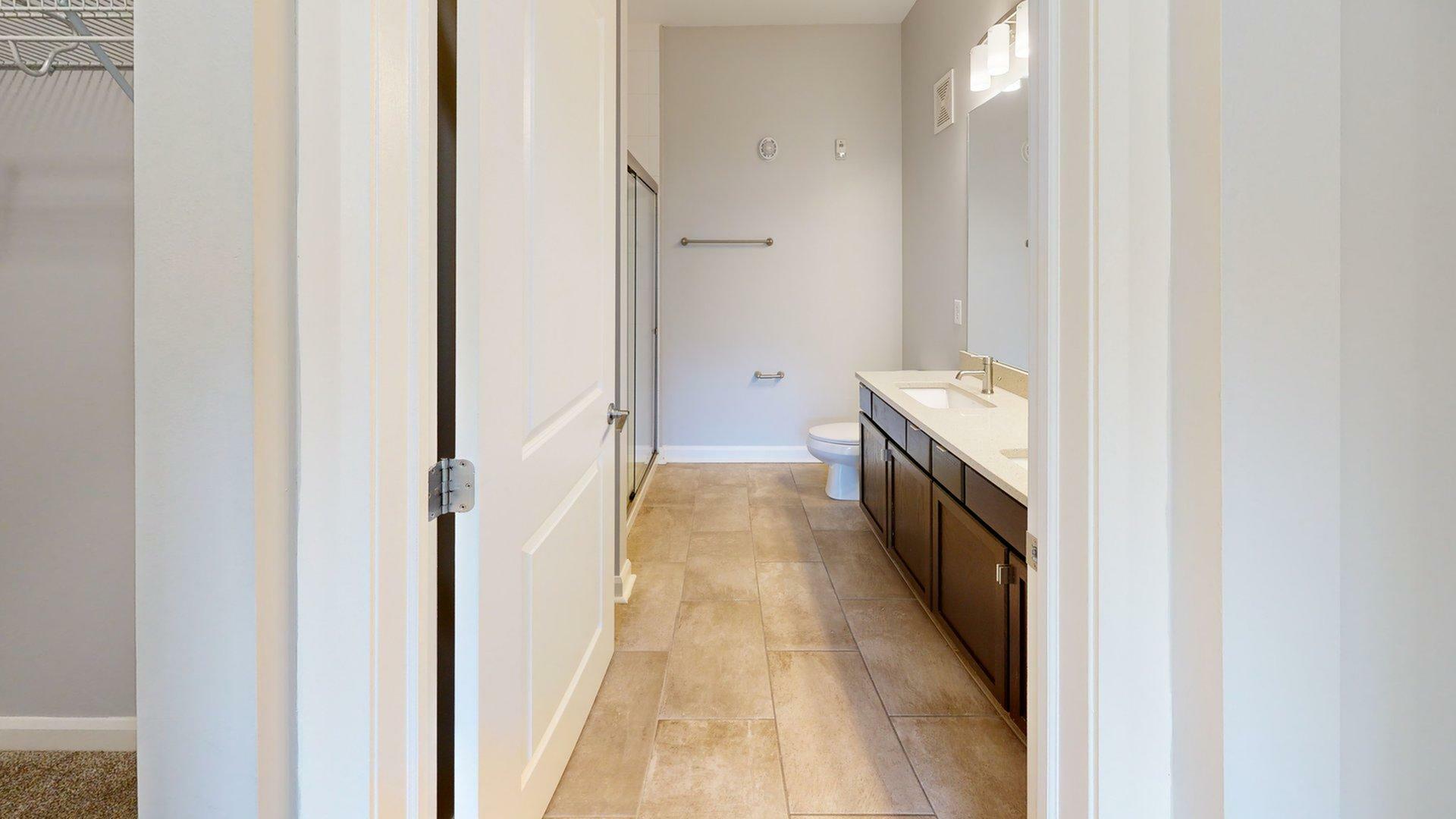 Elegant bathroom with sleek tile flooring, modern vanity, and a spacious shower for a luxurious living experience.