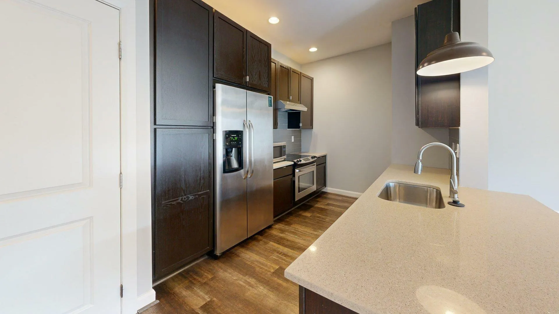 Modern kitchen with sleek dark cabinets, stainless steel appliances, and a stylish countertop, offering a perfect blend of functionality and elegance.