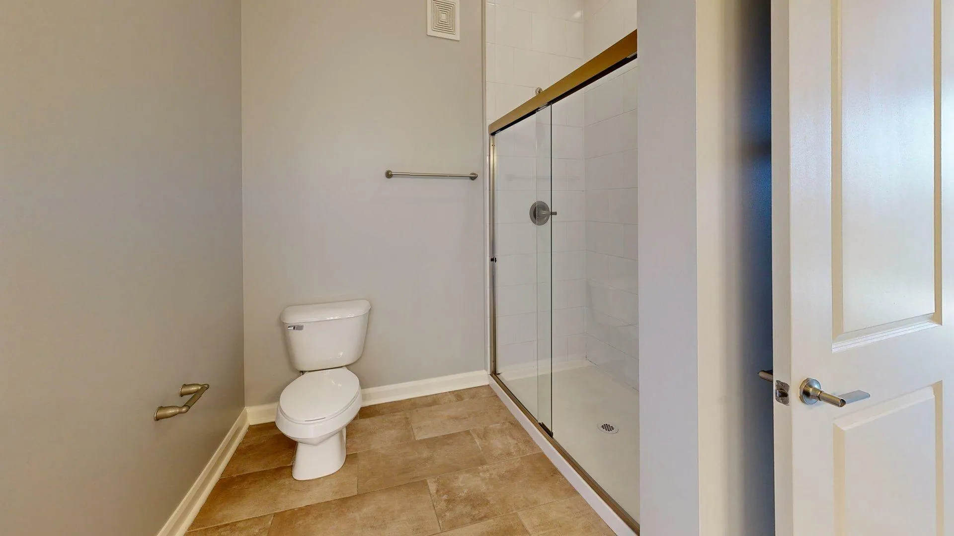 Modern bathroom with a sleek glass shower and elegant tiling in a sophisticated apartment setting.
