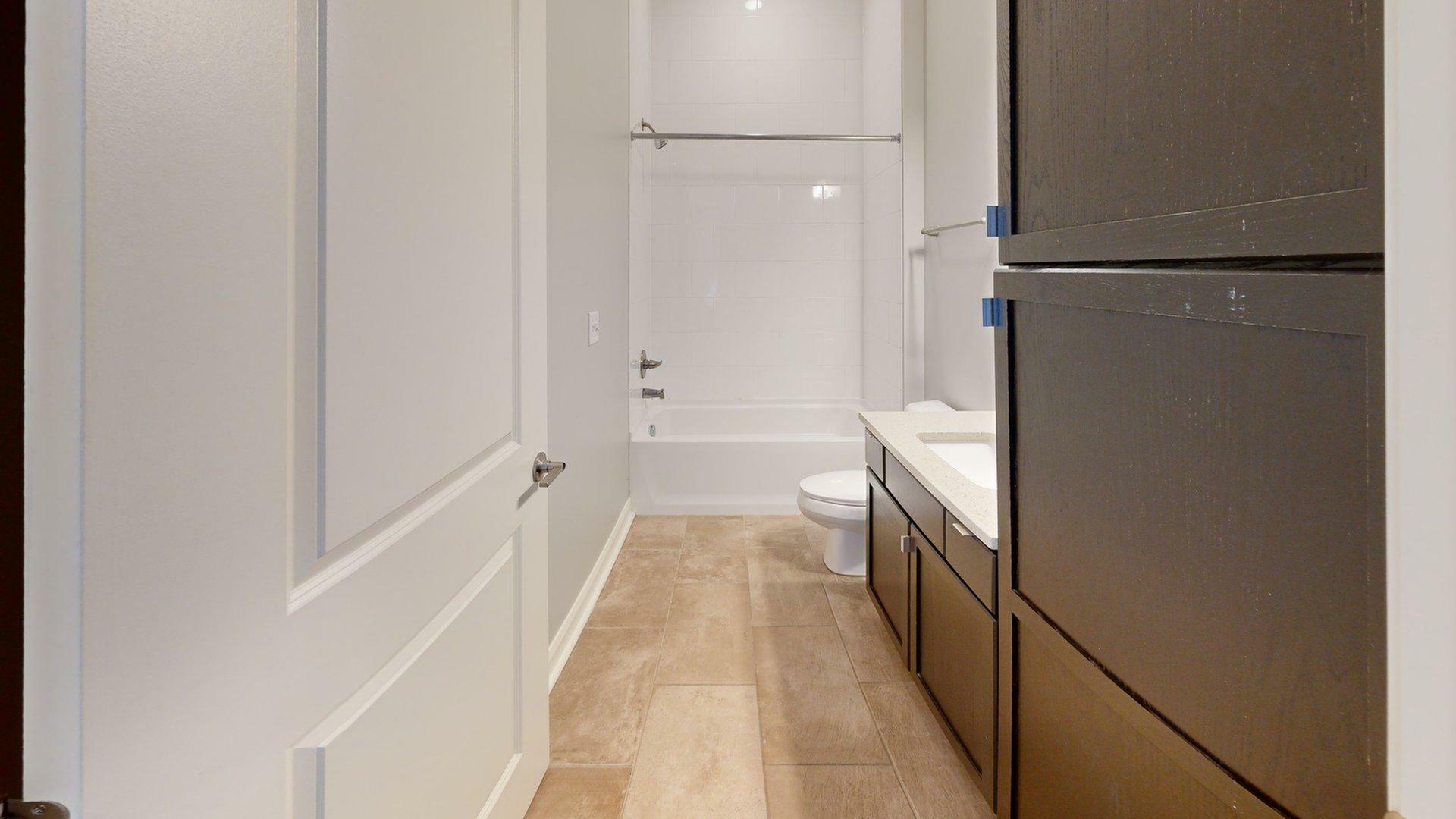 Elegant bathroom with modern fixtures, pristine white tiles, and ample storage space.