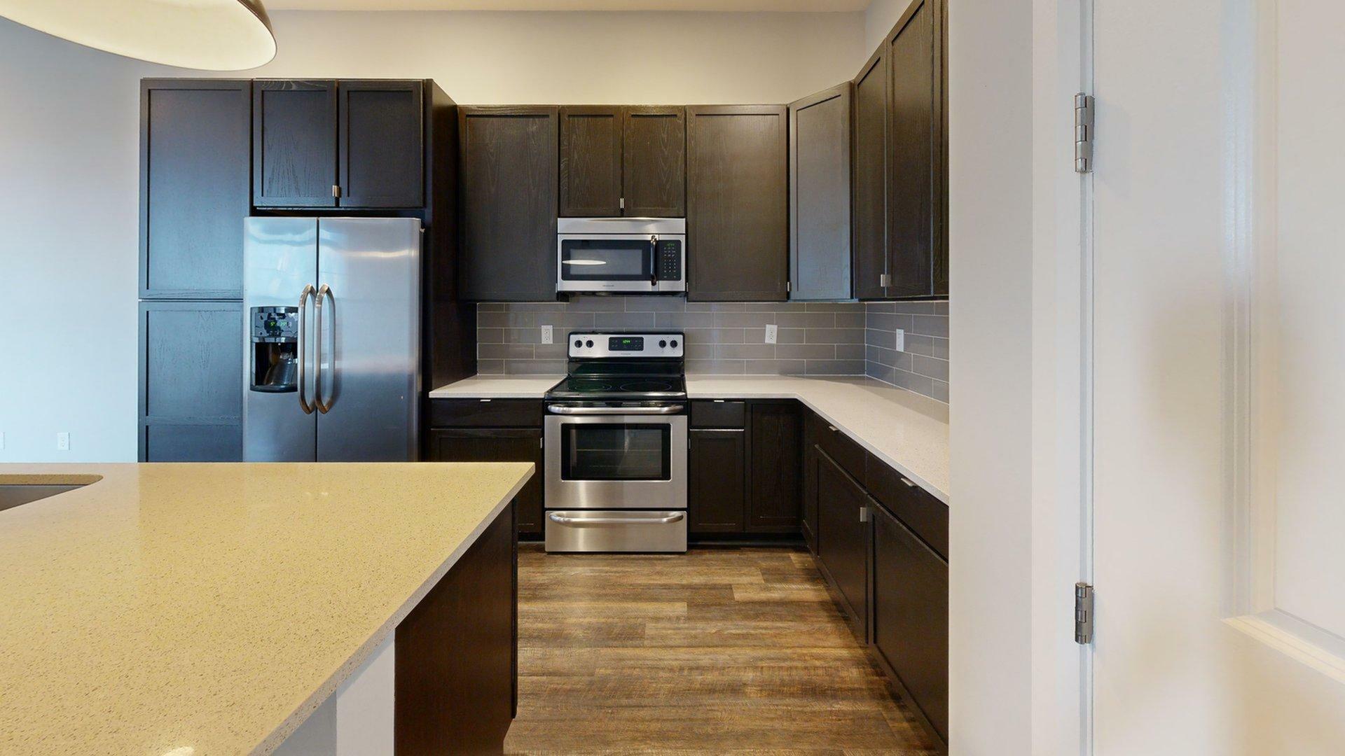 Modern kitchen featuring sleek dark cabinetry, stainless steel appliances, and a spacious countertop.