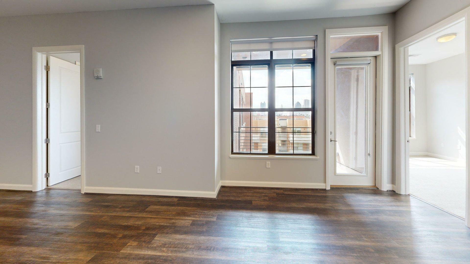 Bright modern apartment interior featuring large windows, elegant hardwood floors, and ample natural light.