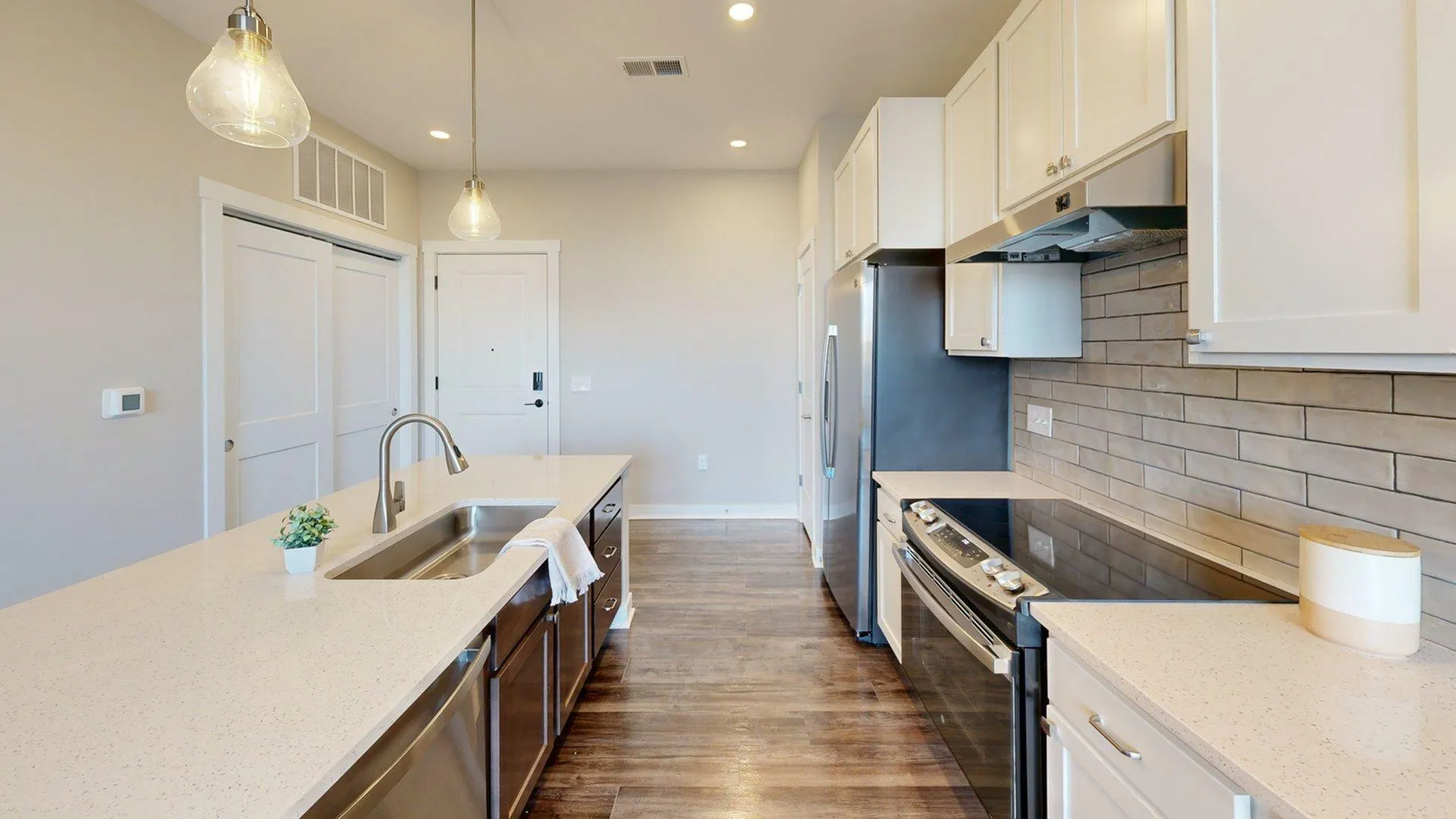Modern kitchen with sleek countertops, elegant lighting, and stainless steel appliances.