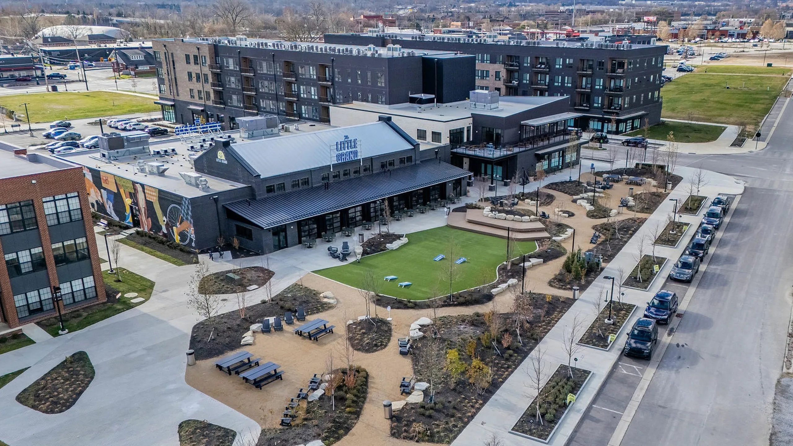 Aerial view of a modern community center with landscaped gardens, outdoor seating, and spacious parking in an urban neighborhood.