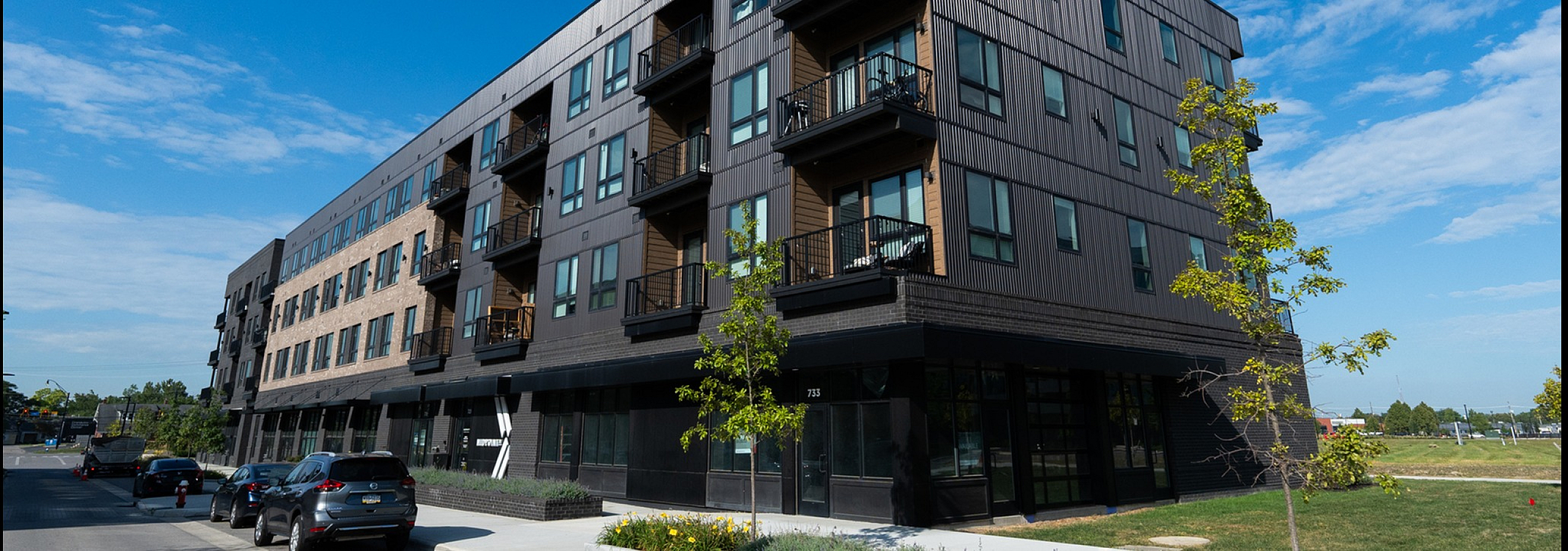 Contemporary apartment building with sleek design, featuring multiple balconies and large windows.