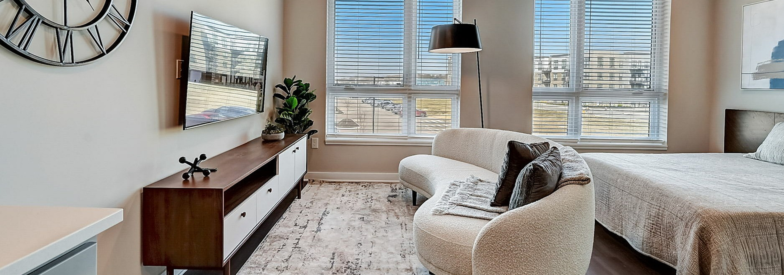Modern bedroom with large windows, contemporary decor, and cozy seating area.