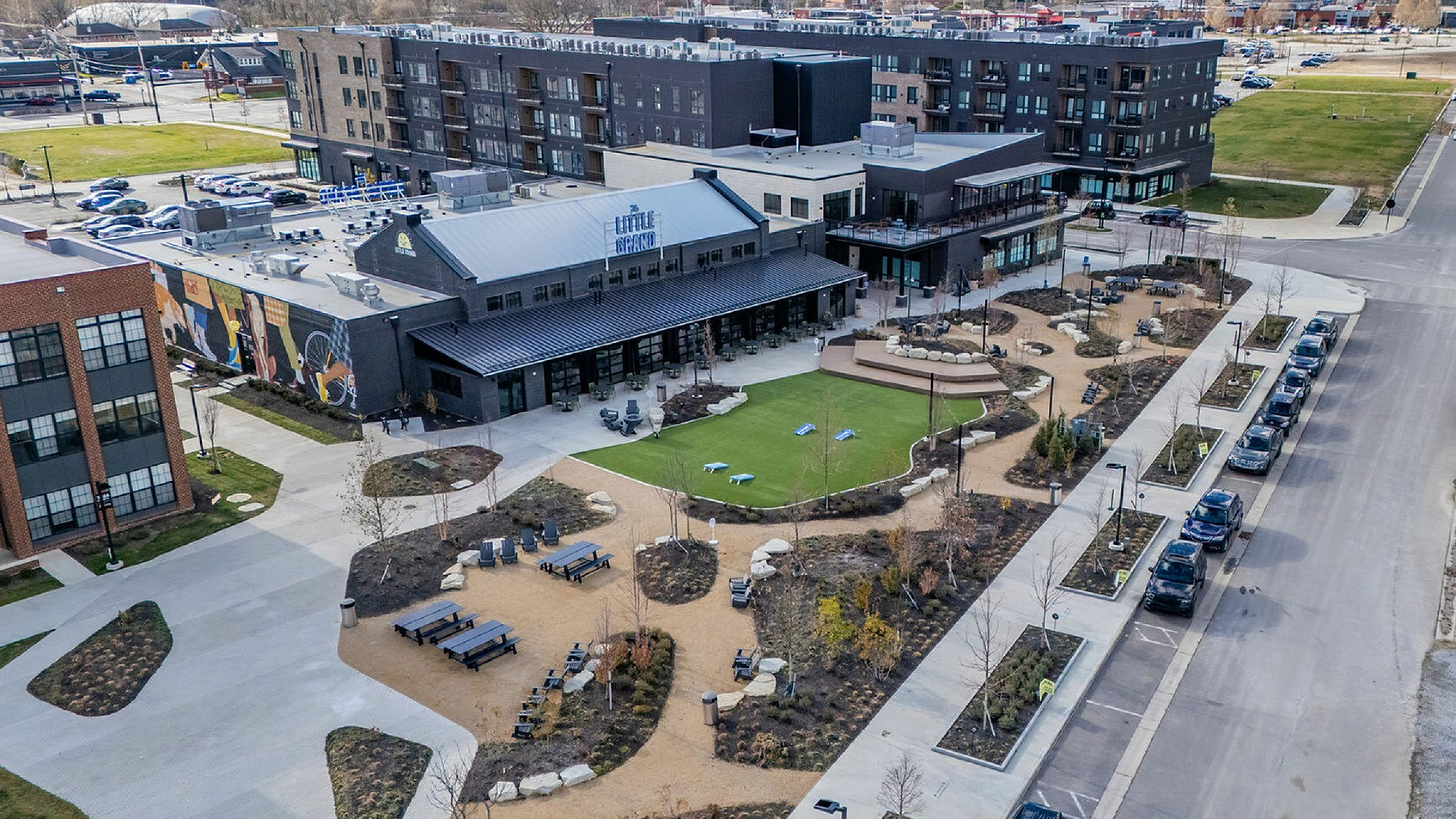 Aerial view of a contemporary community space featuring landscaped gardens, outdoor seating, and nearby modern apartments.