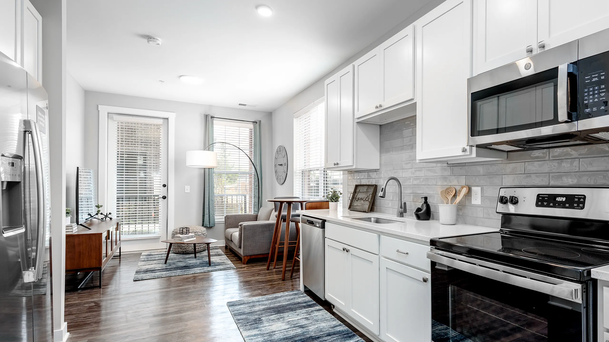 Bright and modern open kitchen with stainless steel appliances leading to a cozy living area.