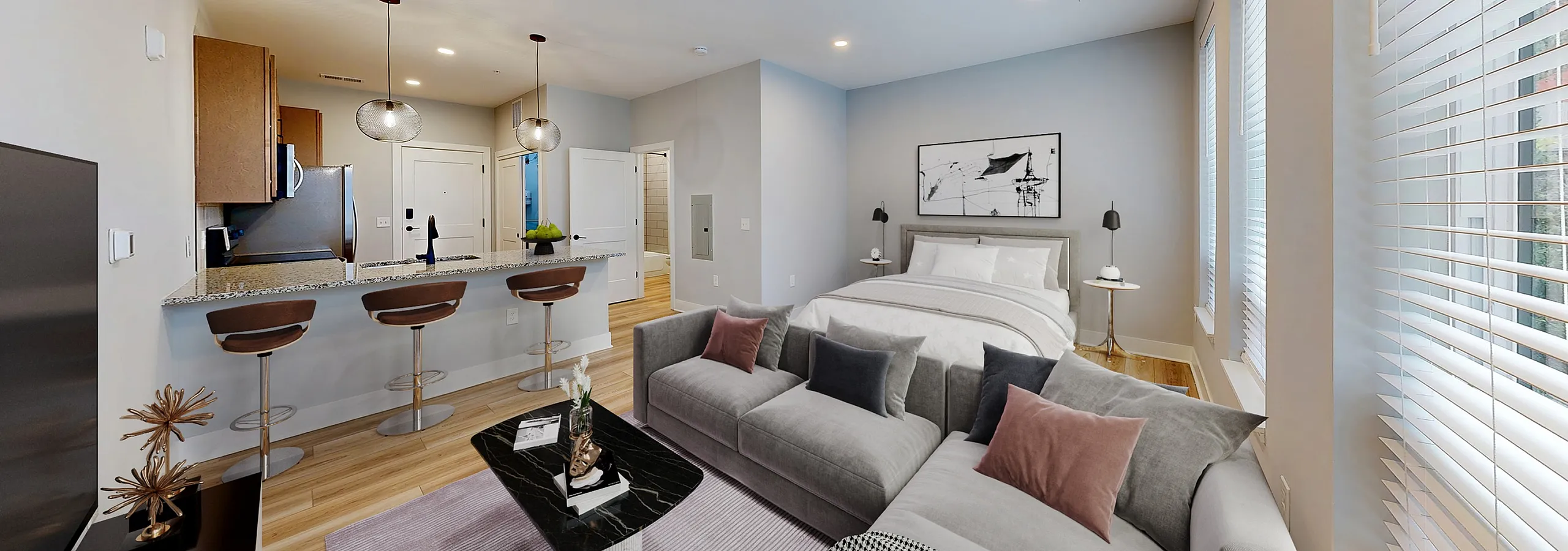 Modern studio apartment with an open floor plan, featuring a cozy living area, stylish kitchen with bar seating, and a luxurious bed by large windows bringing in natural light.