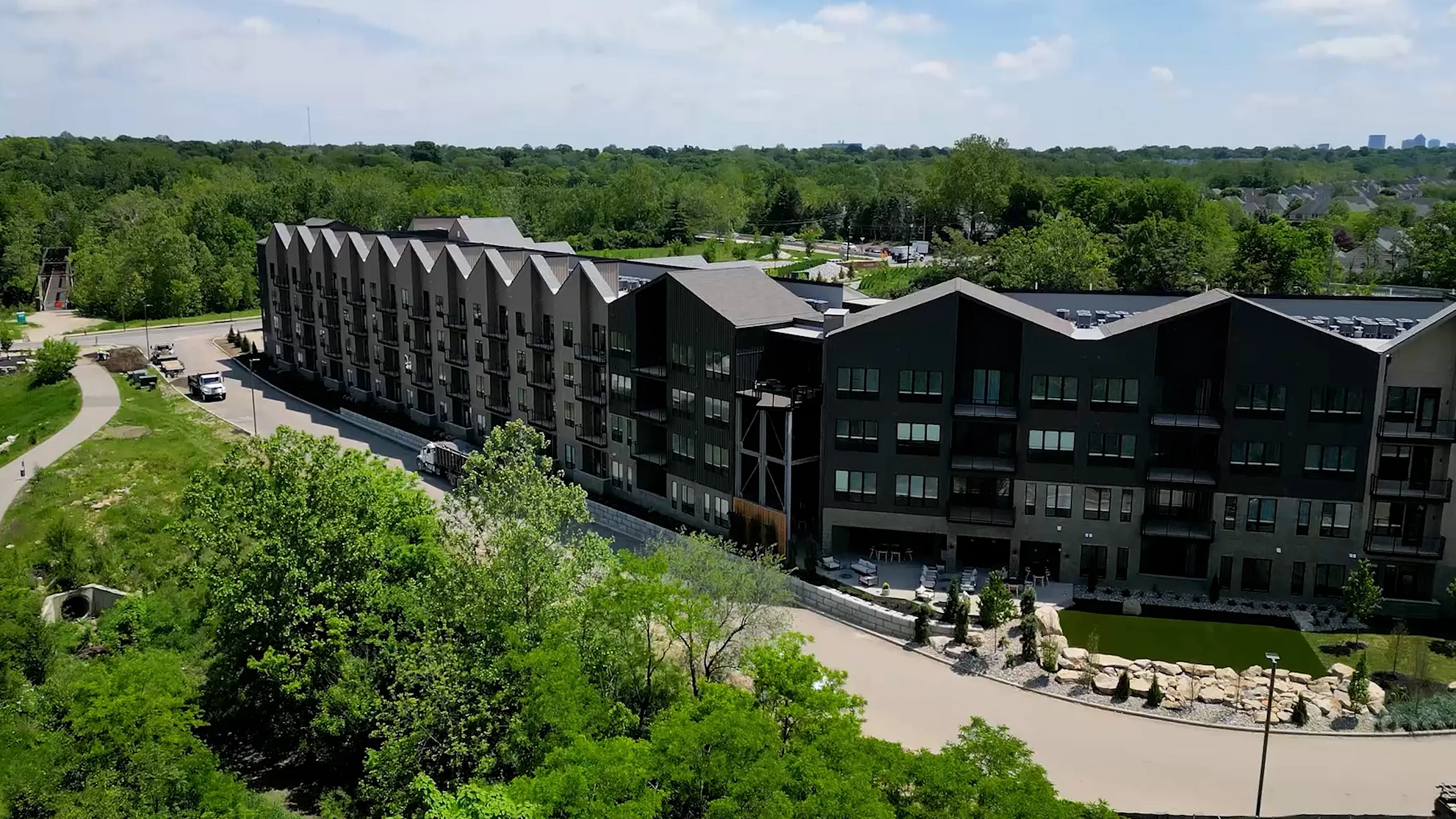 Modern apartment complex nestled in lush greenery, featuring unique architecture and scenic surroundings.