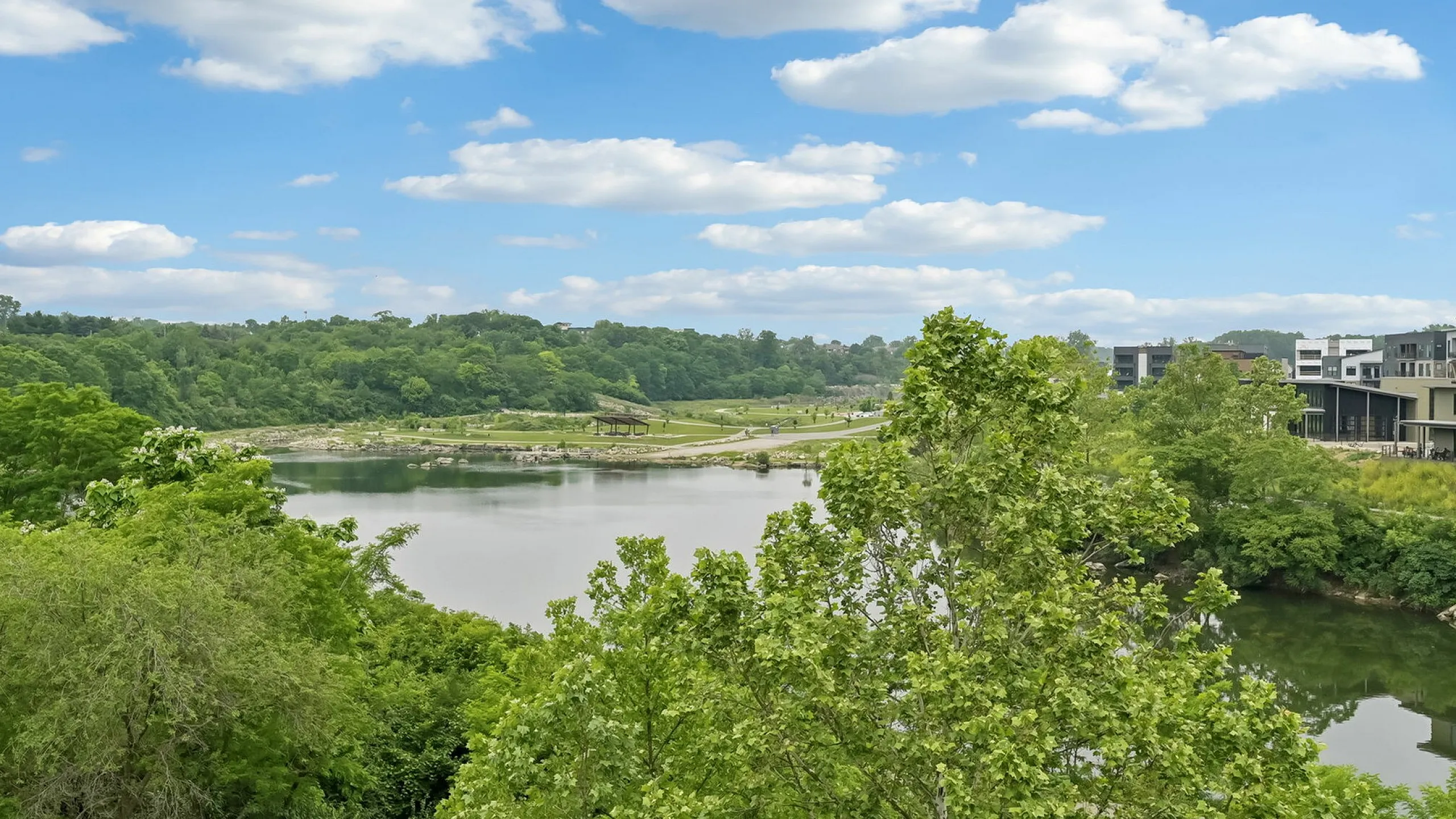 Breathtaking view of lush greenery surrounding a serene lake under a vibrant blue sky, enhancing apartment appeal with natural beauty.