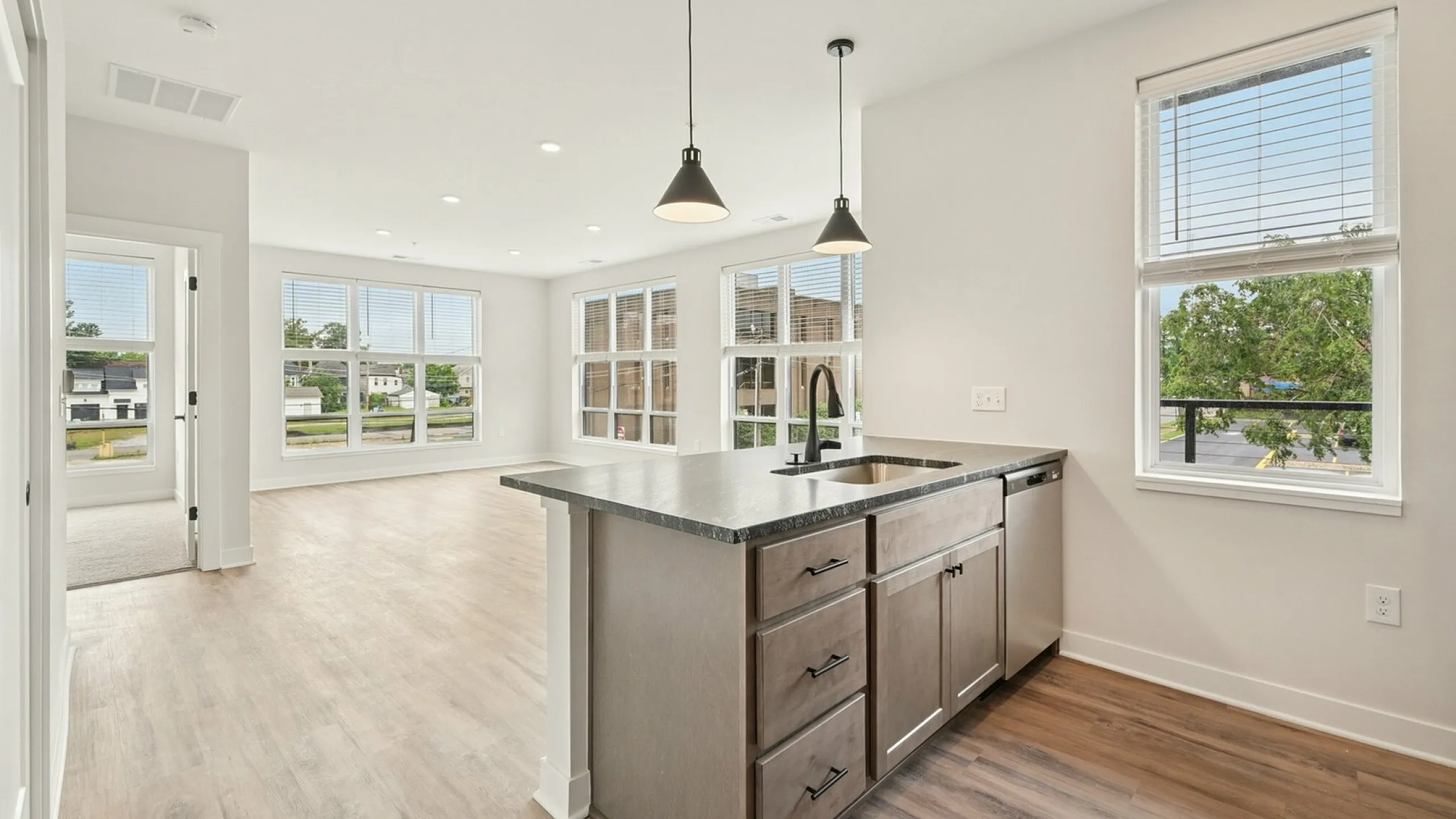 Bright and modern open-concept kitchen and living area with sleek countertops, ample natural light, and stylish pendant lighting.