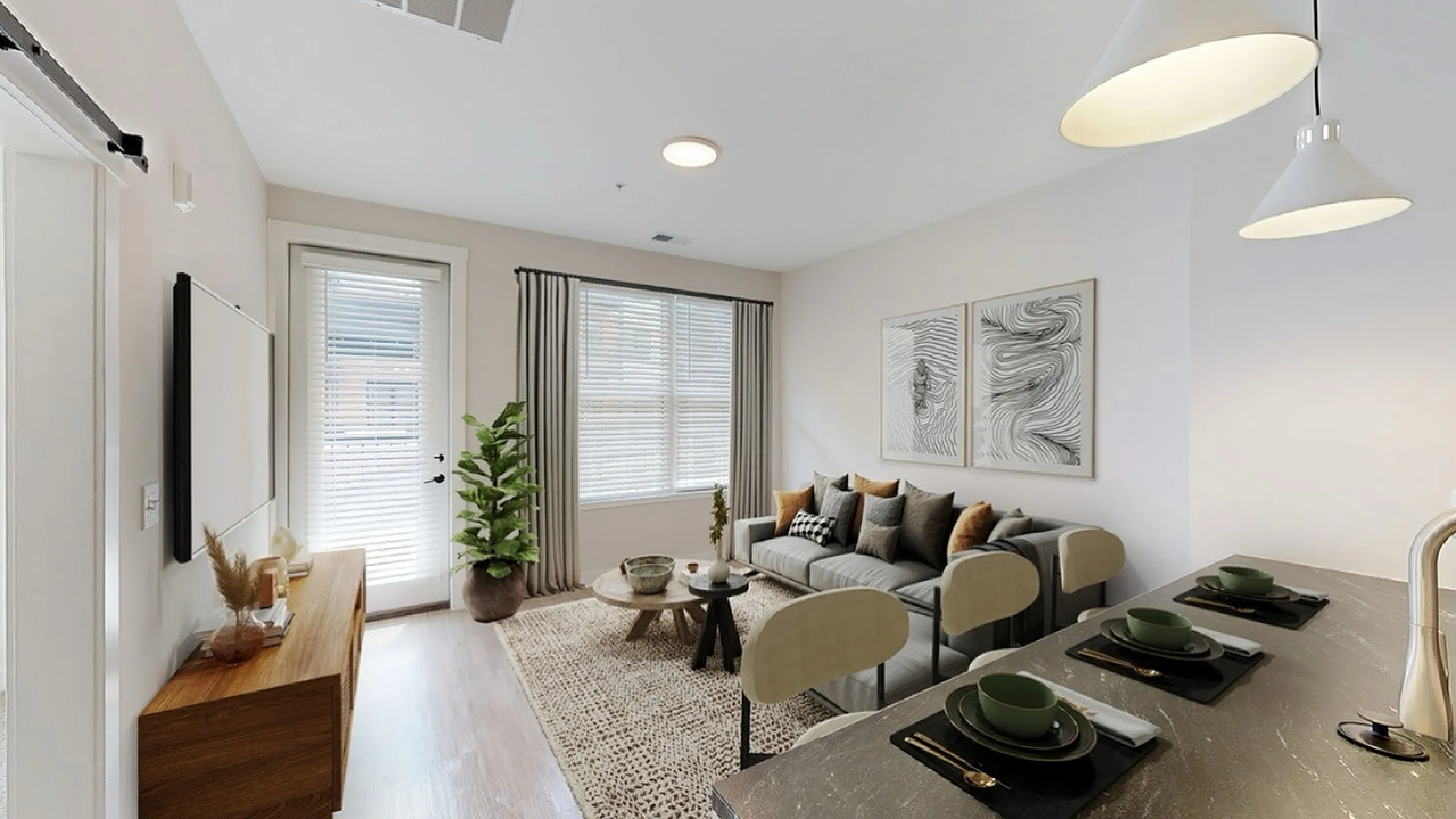 Elegant living room with modern decor featuring a cozy grey sofa, stylish artwork, and a breakfast bar with chic pendant lighting.
