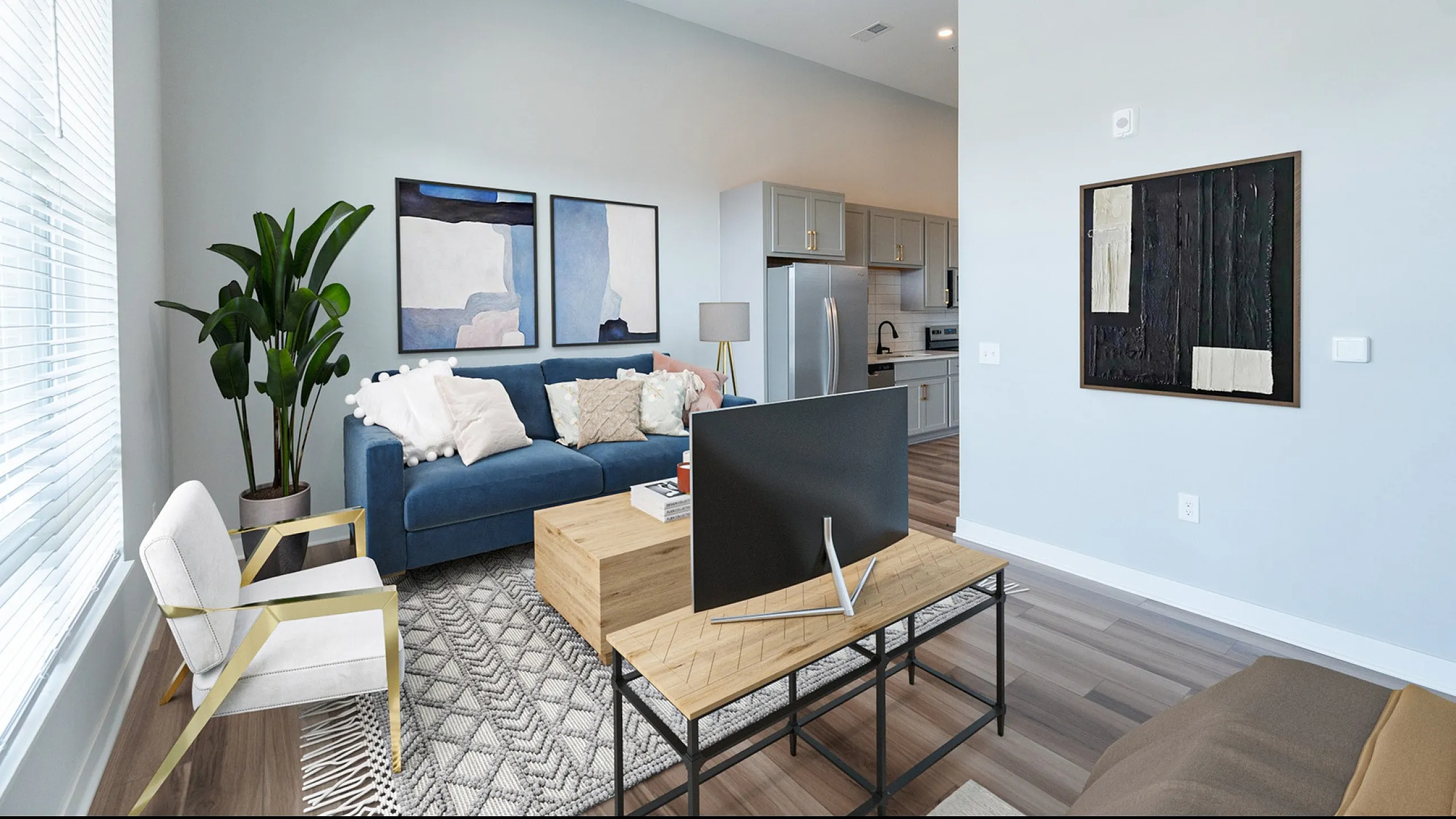 Inviting modern living room with a chic blue sofa, elegant artwork, and a stylish open kitchen layout.
