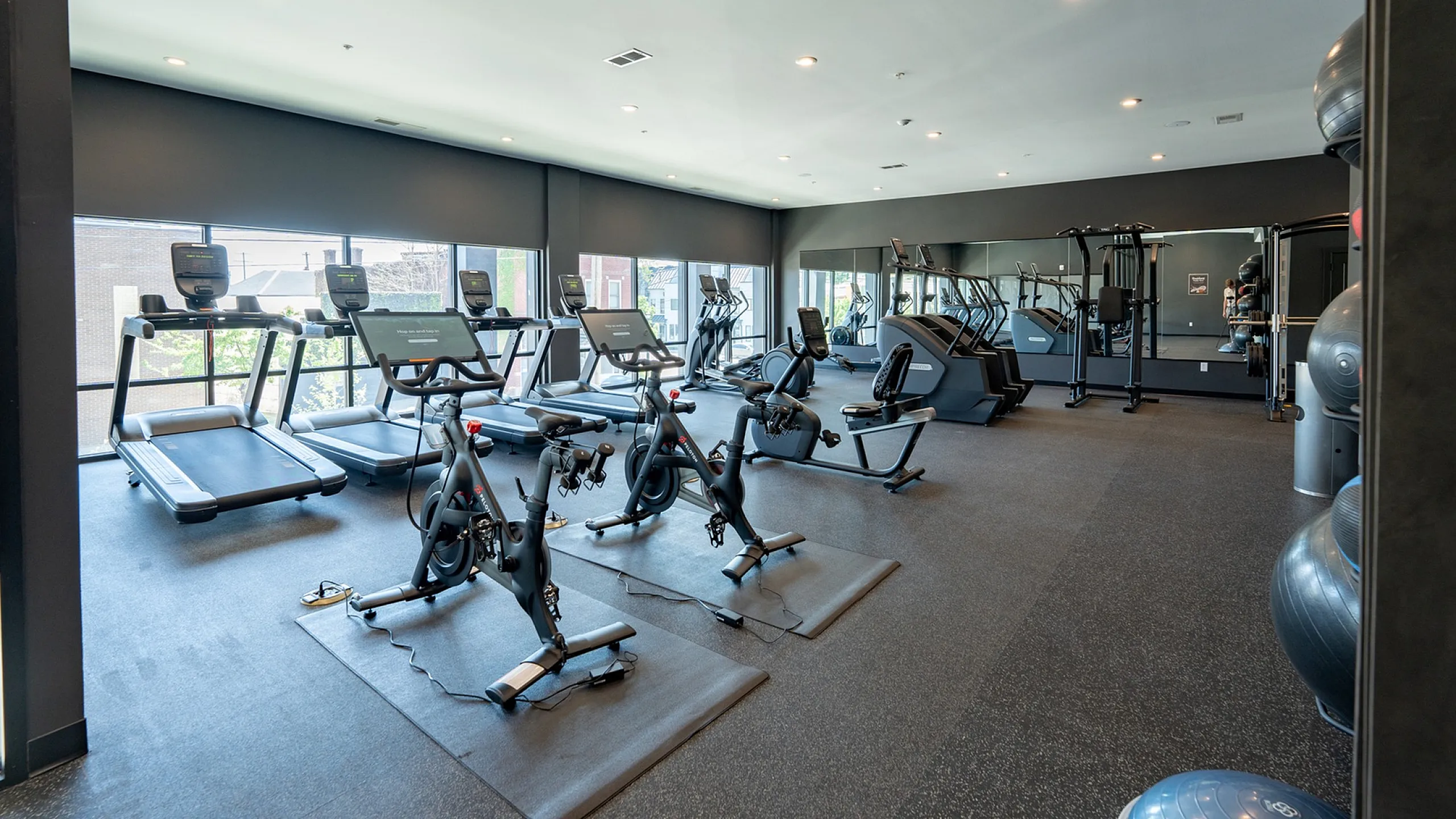 Modern fitness center with state-of-the-art exercise equipment, bright open space, and floor-to-ceiling windows.