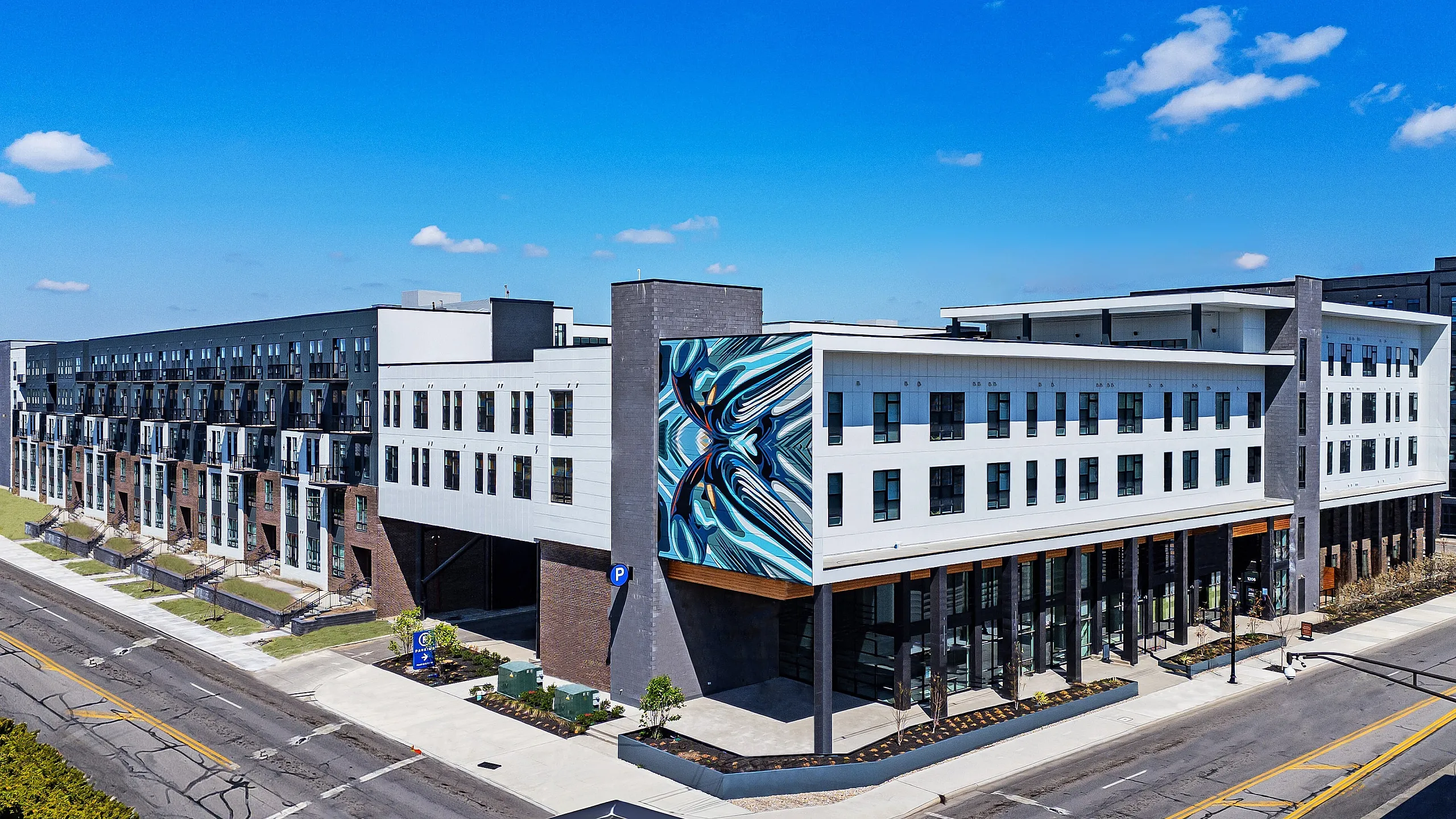 Contemporary apartment building with eye-catching street art and modern facade, featuring large windows and vibrant urban setting.