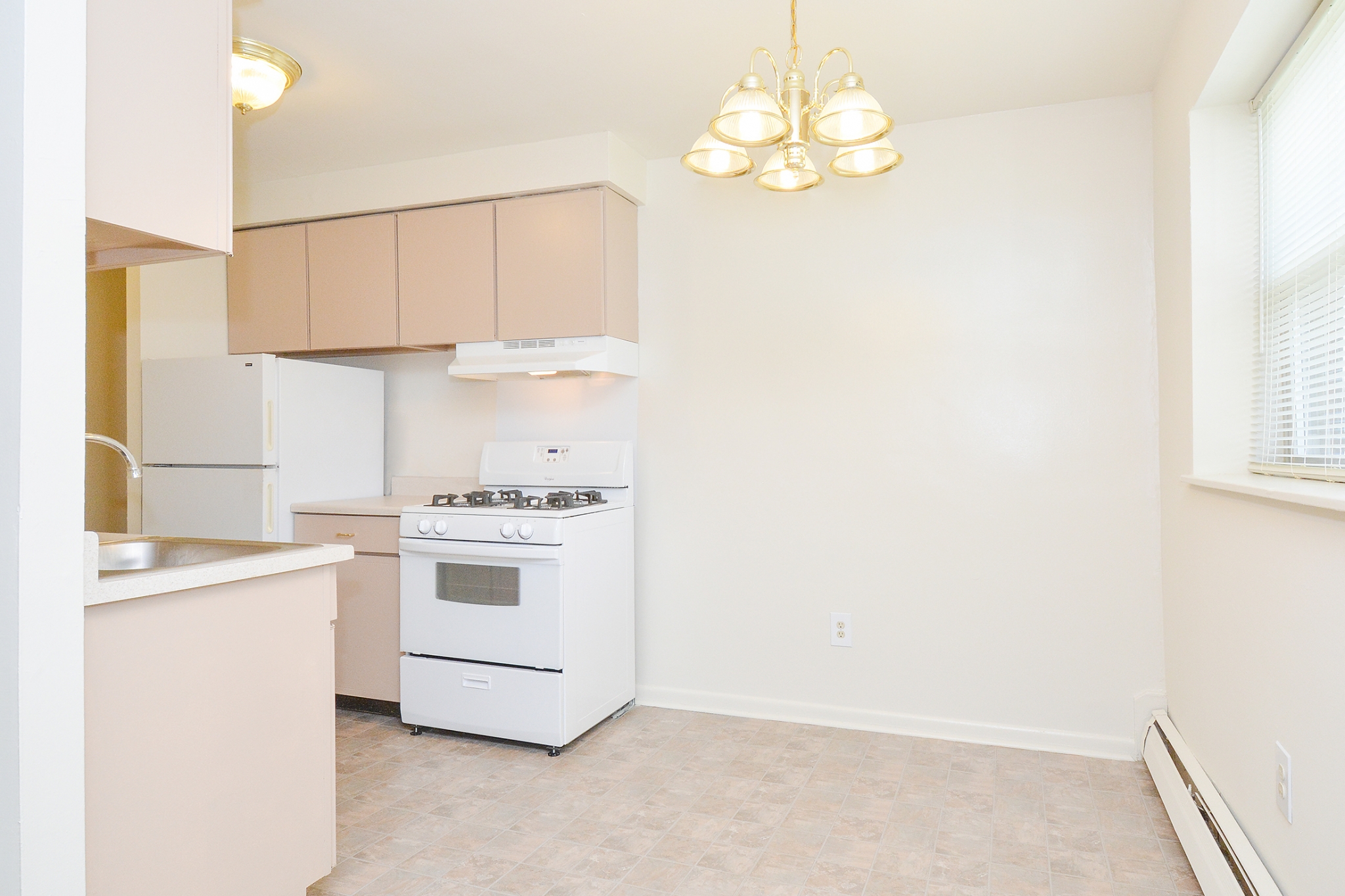 Newport Village Sample Dining Room with Chandelier and white Appliances | Levittown PA Apartments