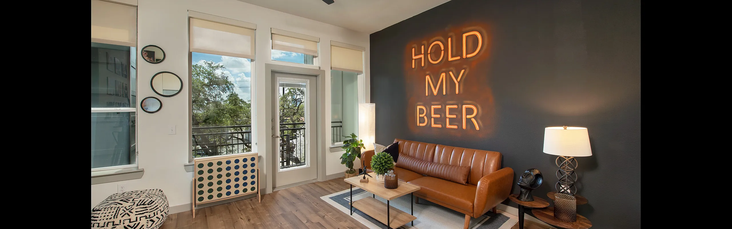 Chic living room with modern decor, stylish leather sofa, and illuminated 'Hold My Beer' wall art creating a cozy ambience.