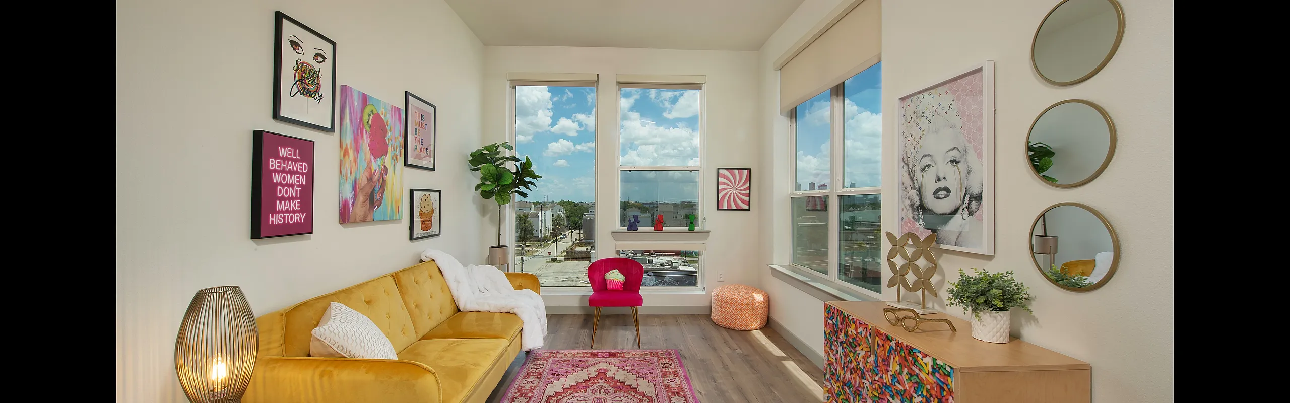 Vibrant modern living room with colorful decor, featuring a cozy yellow sofa, artistic gallery wall, and large windows offering stunning views.
