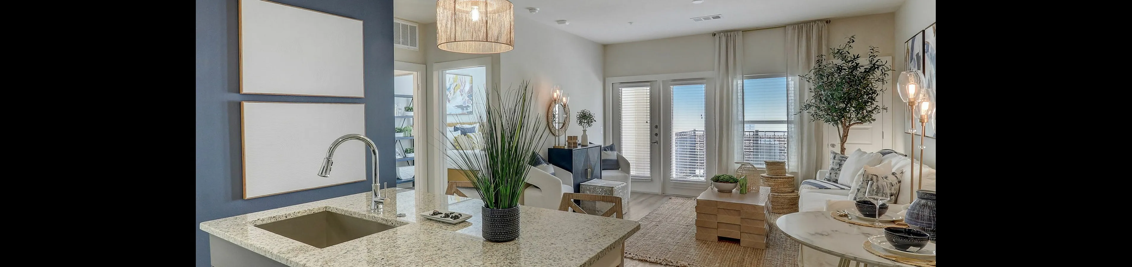 Elegant open-plan apartment showcasing a modern kitchen with granite countertops and a bright living area with chic decor and natural light.