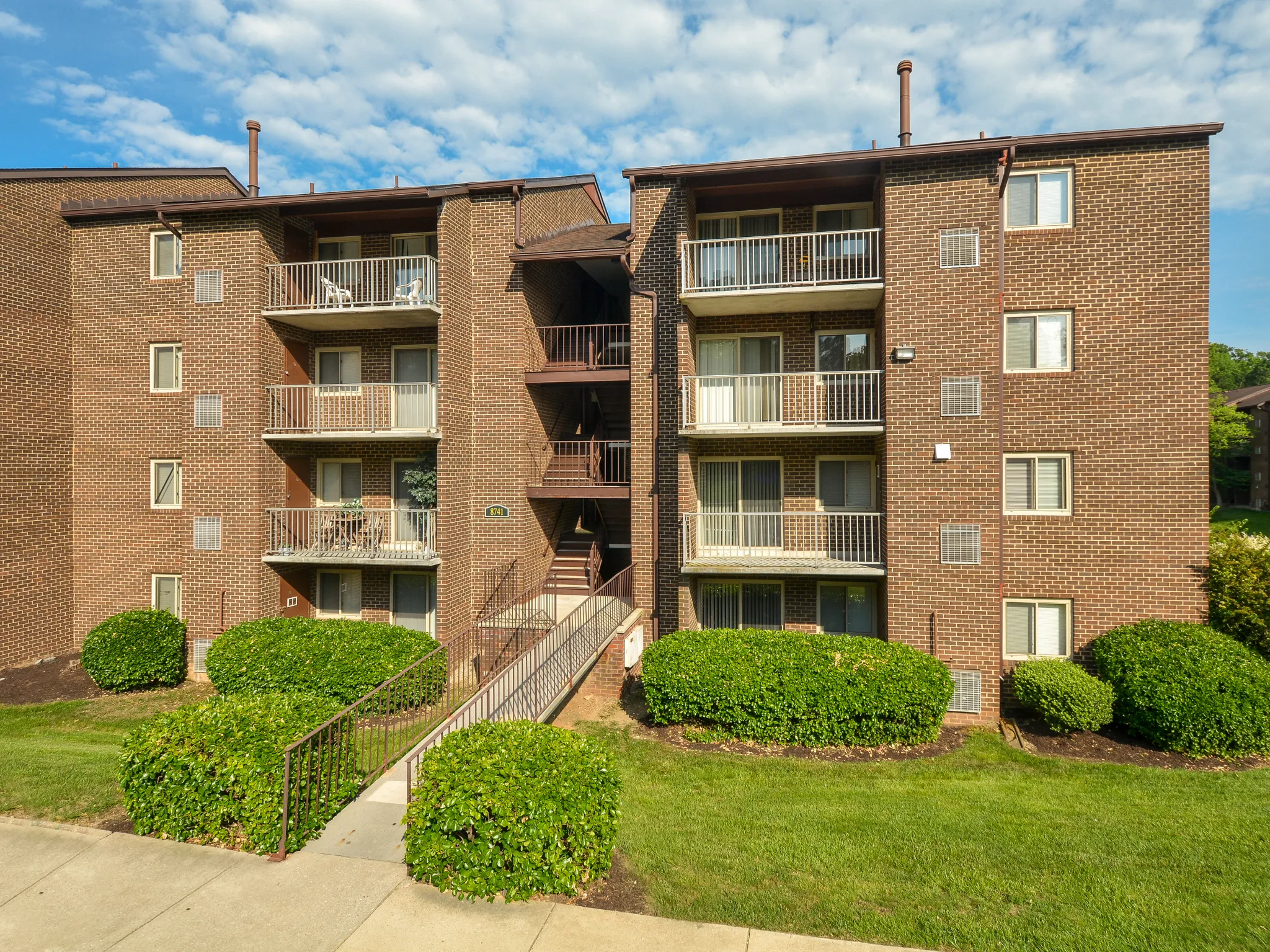 Outdoor apartment building with balconies and bushes.