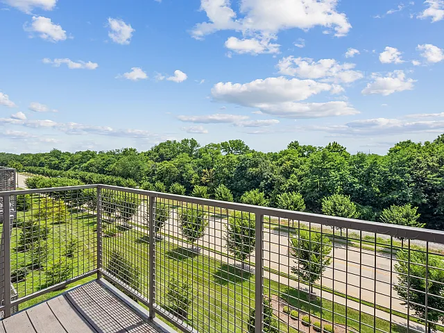 Inviting balcony with stunning views of lush green trees and a bright blue sky, offering a serene retreat in a prime location.