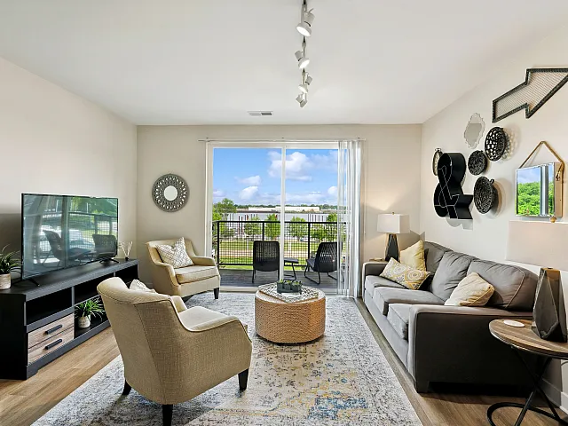 Bright and welcoming living room with modern decor, plush seating, and a view of the scenic outdoors through large sliding glass doors.