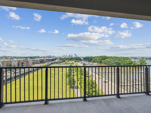 Stunning balcony view showcasing lush green parklands, a vibrant city skyline, and serene waterfront harbor.