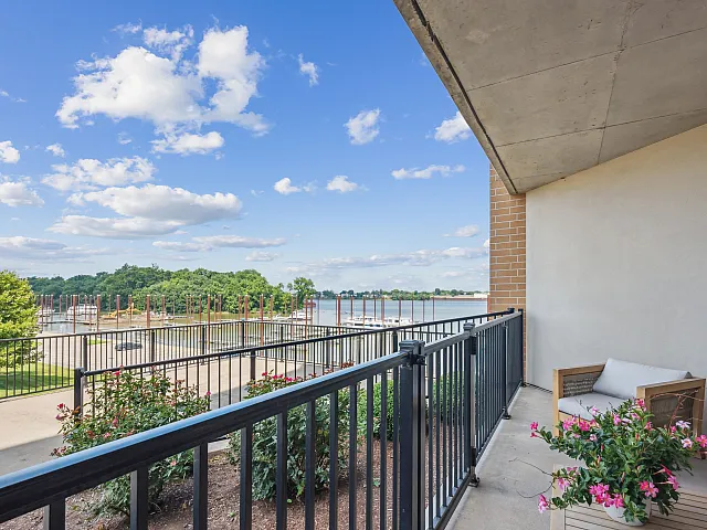 Charming balcony overlooking a serene waterfront with lush greenery, perfect for relaxation and enjoying nature.
