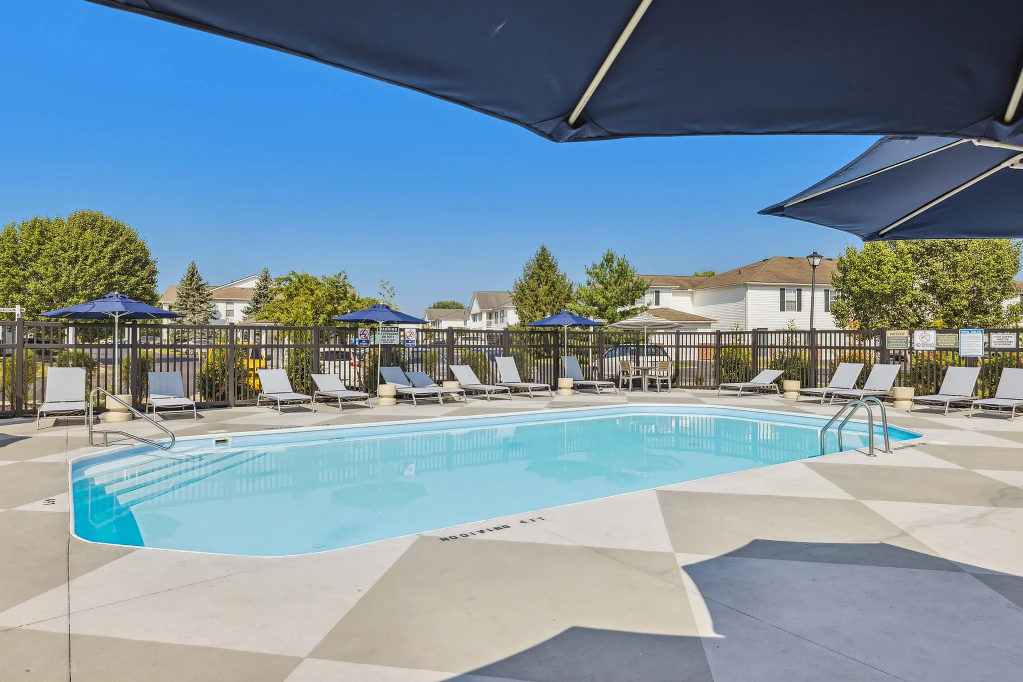 Inviting outdoor pool area with stylish lounge chairs and umbrellas, perfect for relaxation and sunshine enjoyment.