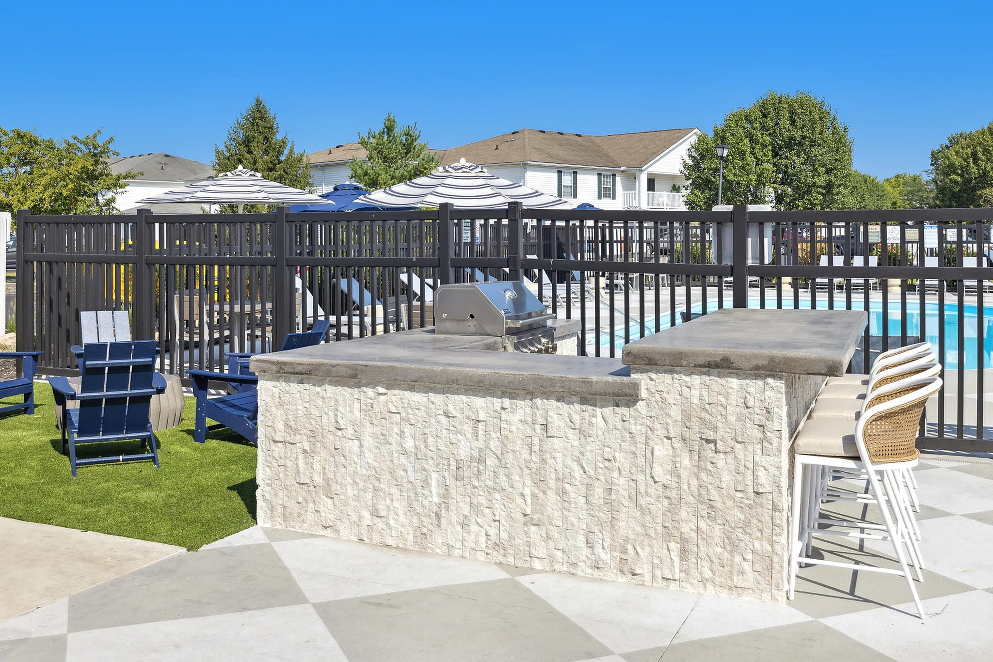 Elegant outdoor patio with modern grill, seating area, and sparkling pool, perfect for relaxation and entertaining.
