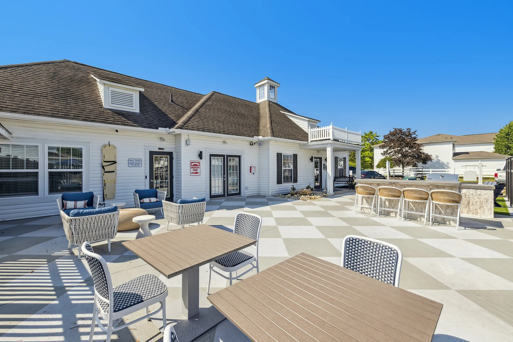 Charming outdoor patio featuring comfortable seating and stylish tables, perfect for gatherings in a bright and inviting residential community.