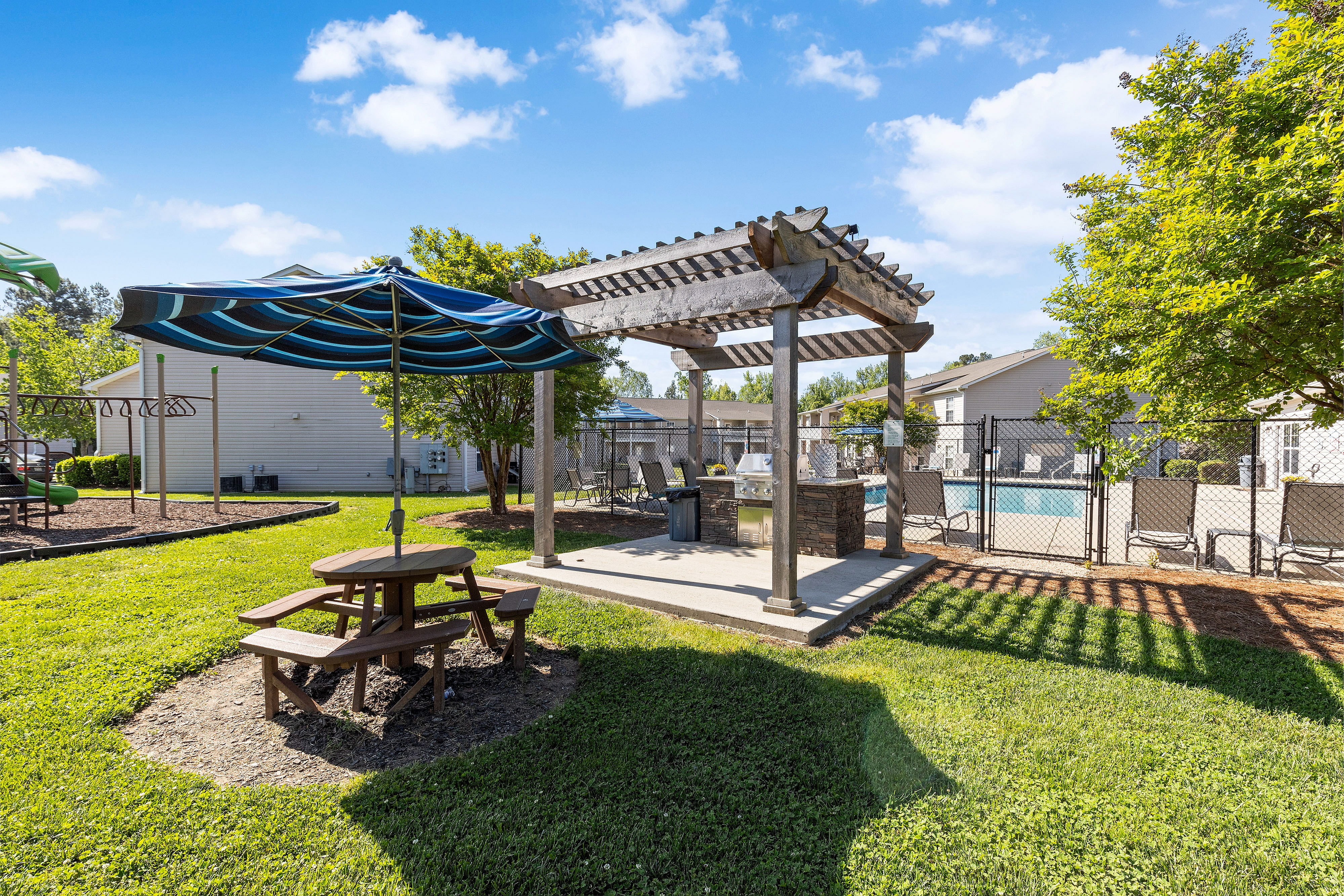 Charming outdoor area with a shaded pergola and picnic table, perfect for relaxation near a sparkling swimming pool.