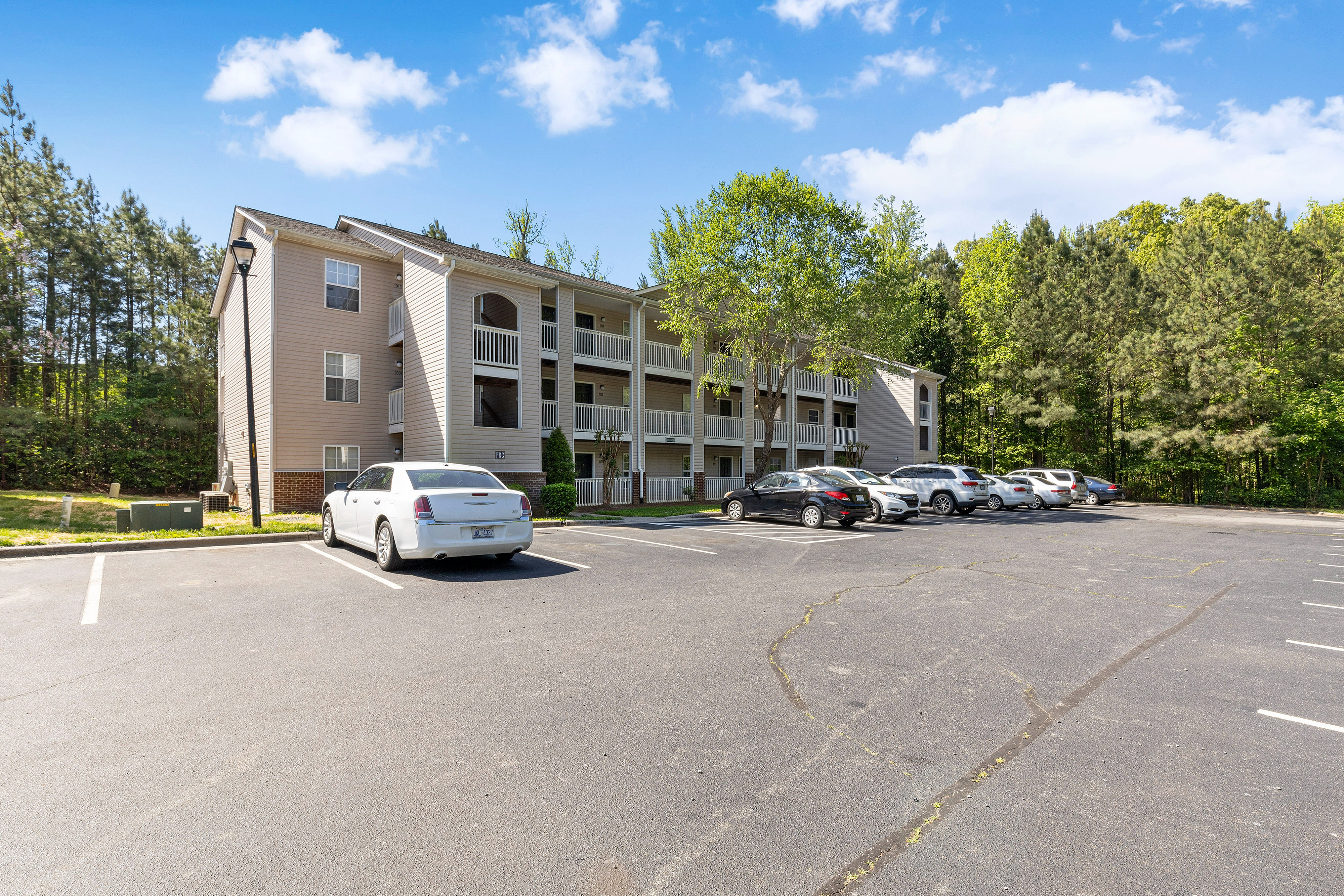 Charming apartment complex nestled in a lush, green setting with ample parking and inviting balconies.