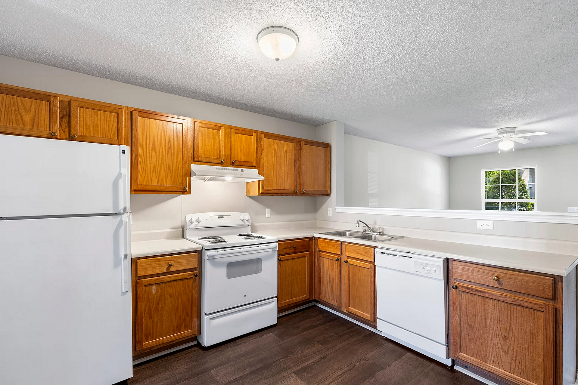 Inviting kitchen with warm wooden cabinetry, sleek white appliances, and elegant open concept design, perfect for modern living.