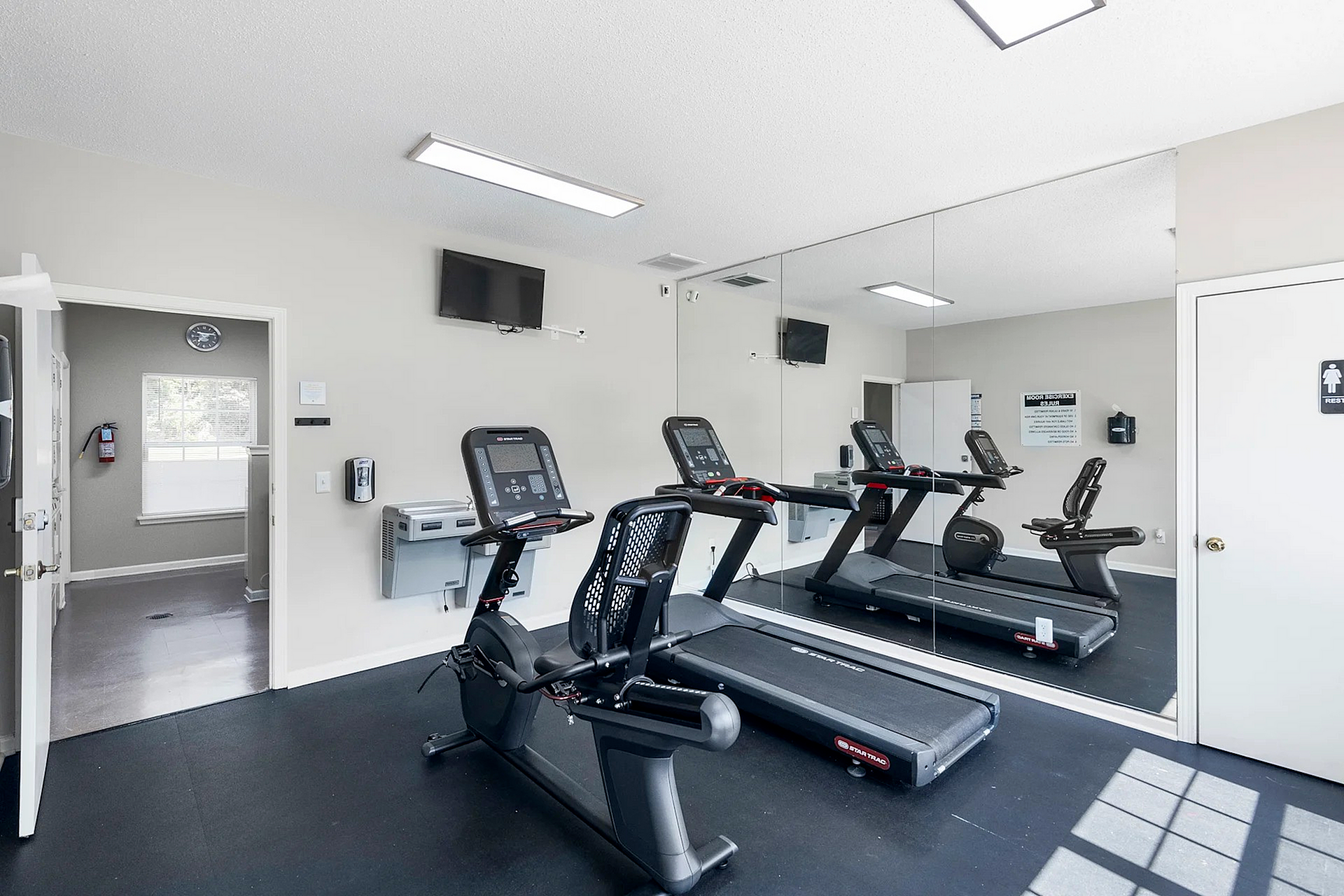 Modern apartment gym featuring state-of-the-art treadmill and exercise bike, bright and inviting with large mirrors.