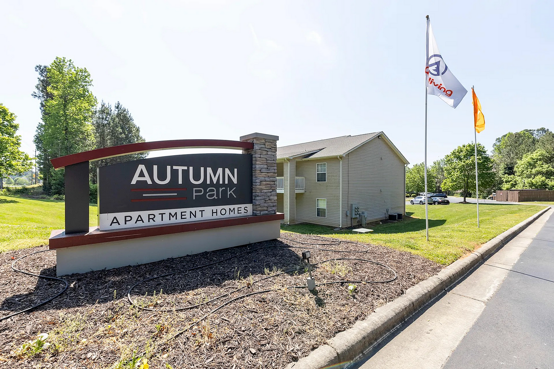 Inviting entrance to Autumn Park Apartment Homes surrounded by lush greenery and modern architecture.