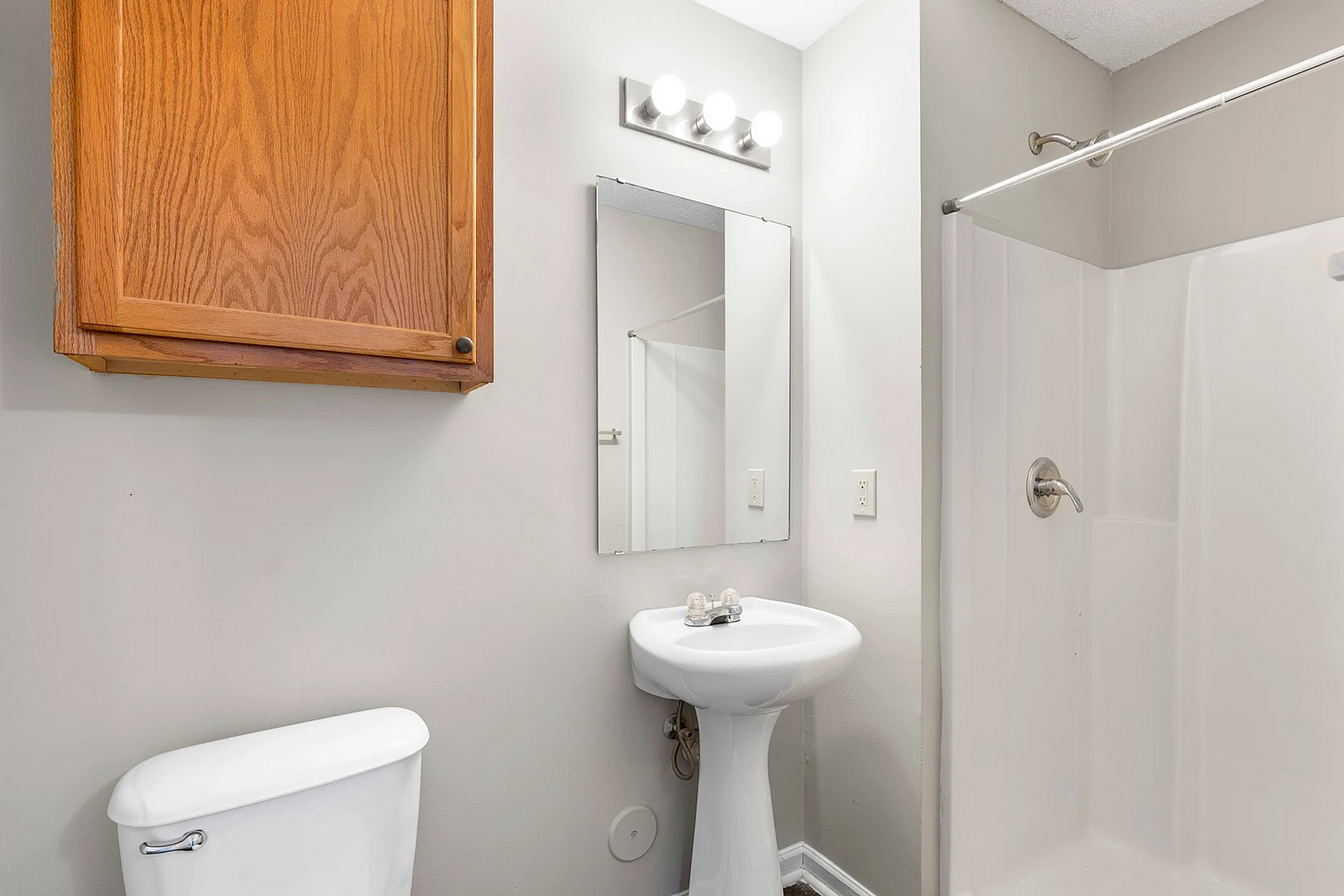 Elegant bathroom featuring a modern pedestal sink, stylish mirror, and sleek shower area with warm lighting.