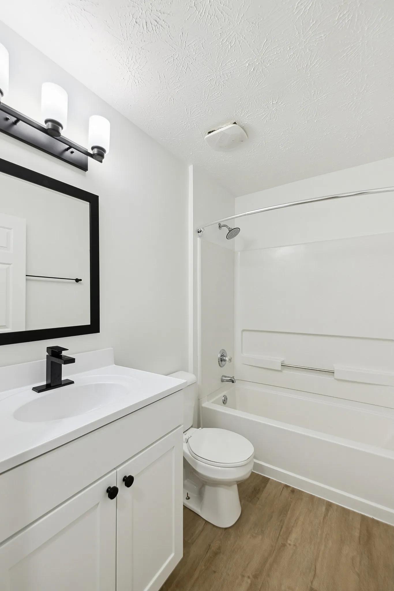Elegant bathroom with modern fixtures, featuring a sleek white vanity, stylish black mirror, and inviting bathtub.